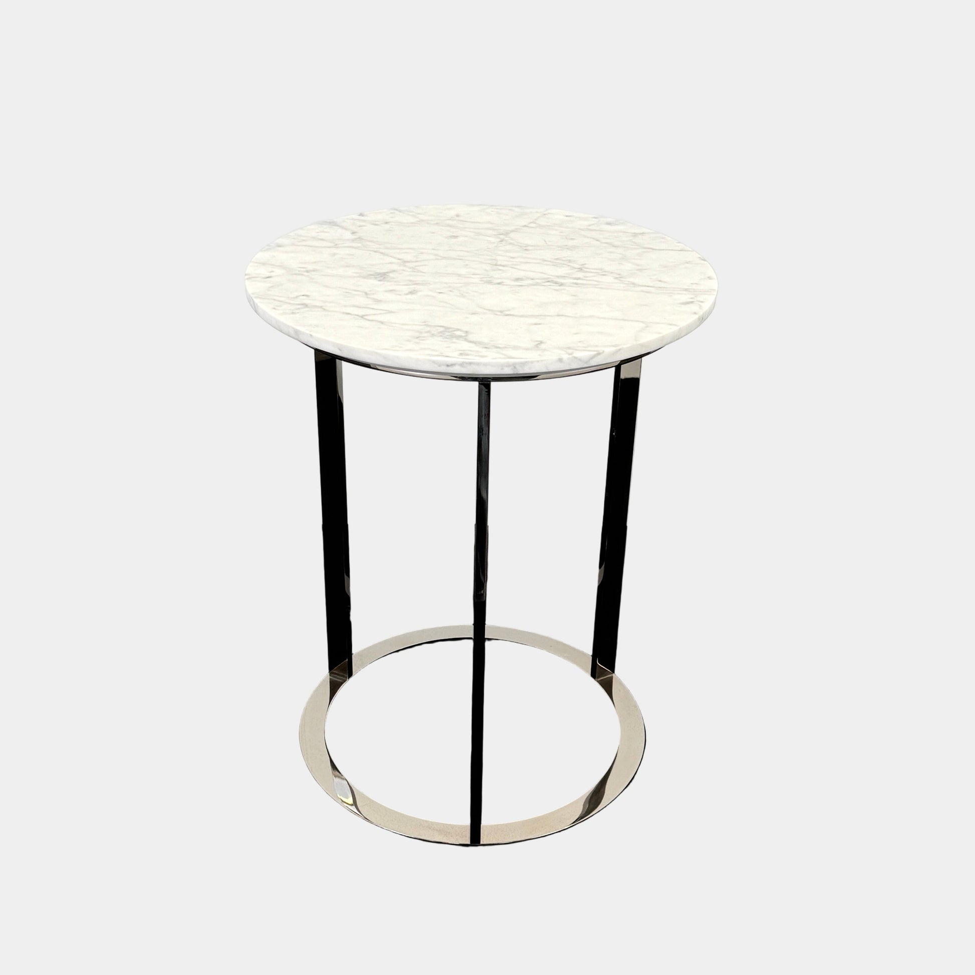 The B&B Italia Mera Accent Table features a round Carrara marble top and a three-legged metal frame with a circular base, showcasing B&B Italia's signature elegance.