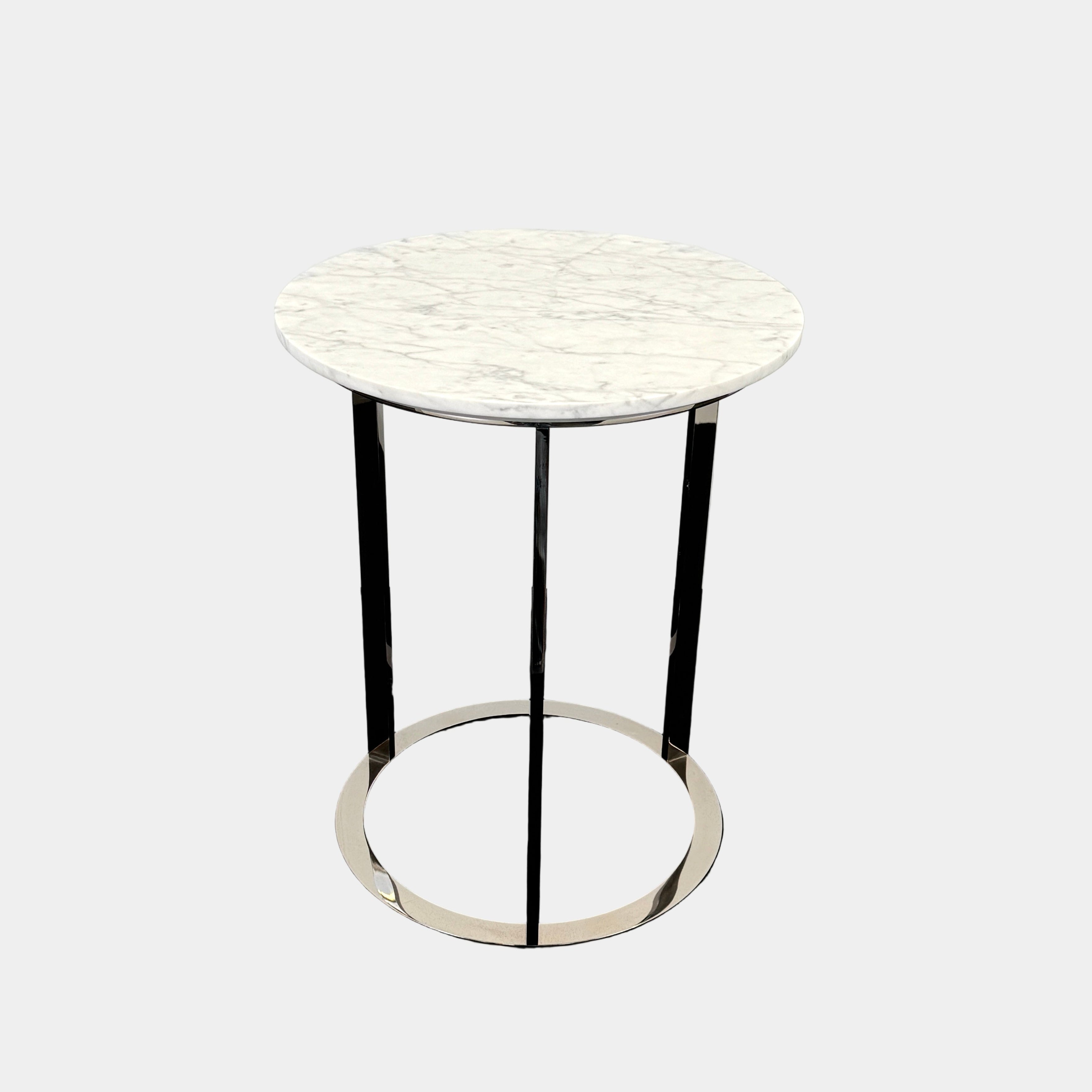 The B&B Italia Mera Accent Table features a round Carrara marble top and a three-legged metal frame with a circular base, showcasing B&B Italia's signature elegance.