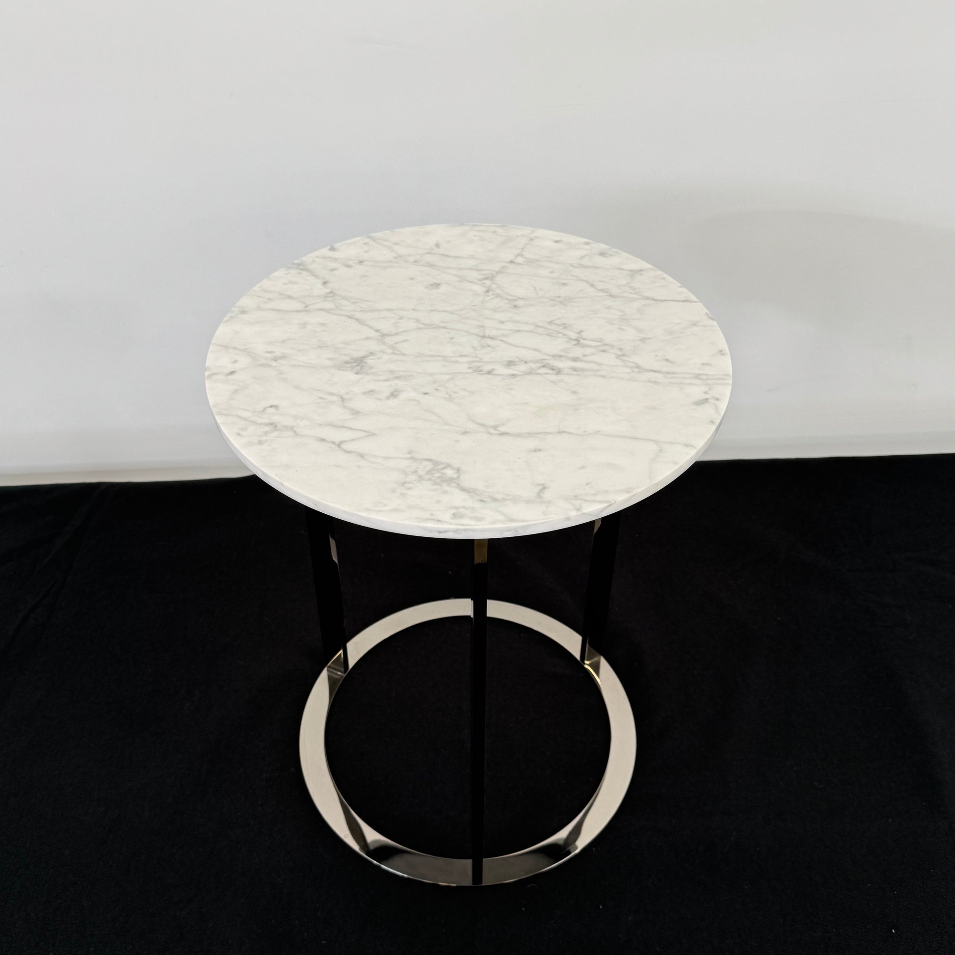 The B&B Italia Mera Accent Table features a round Carrara marble top and a three-legged metal frame with a circular base, showcasing B&B Italia's signature elegance.