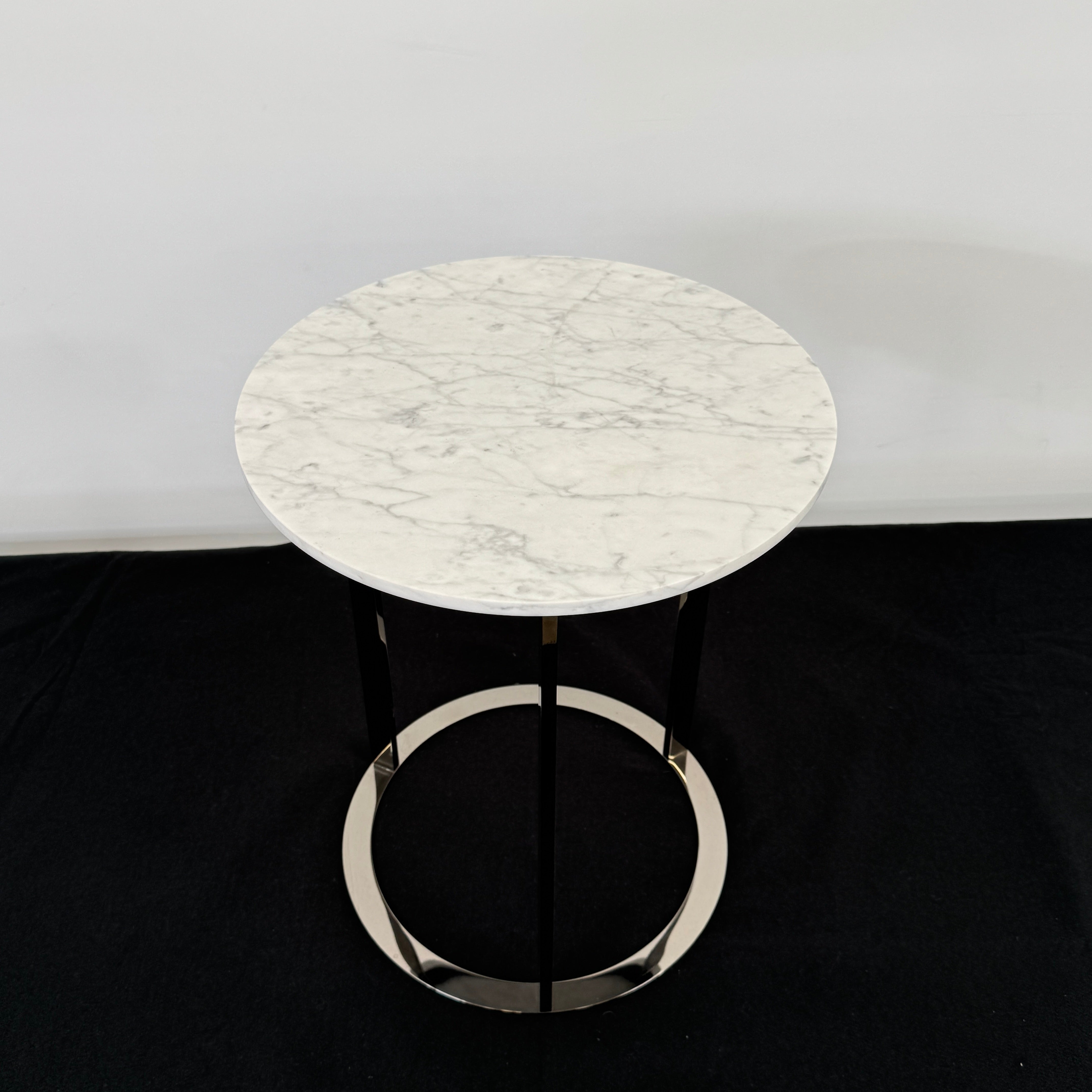 The B&B Italia Mera Accent Table features a round Carrara marble top and a three-legged metal frame with a circular base, showcasing B&B Italia's signature elegance.
