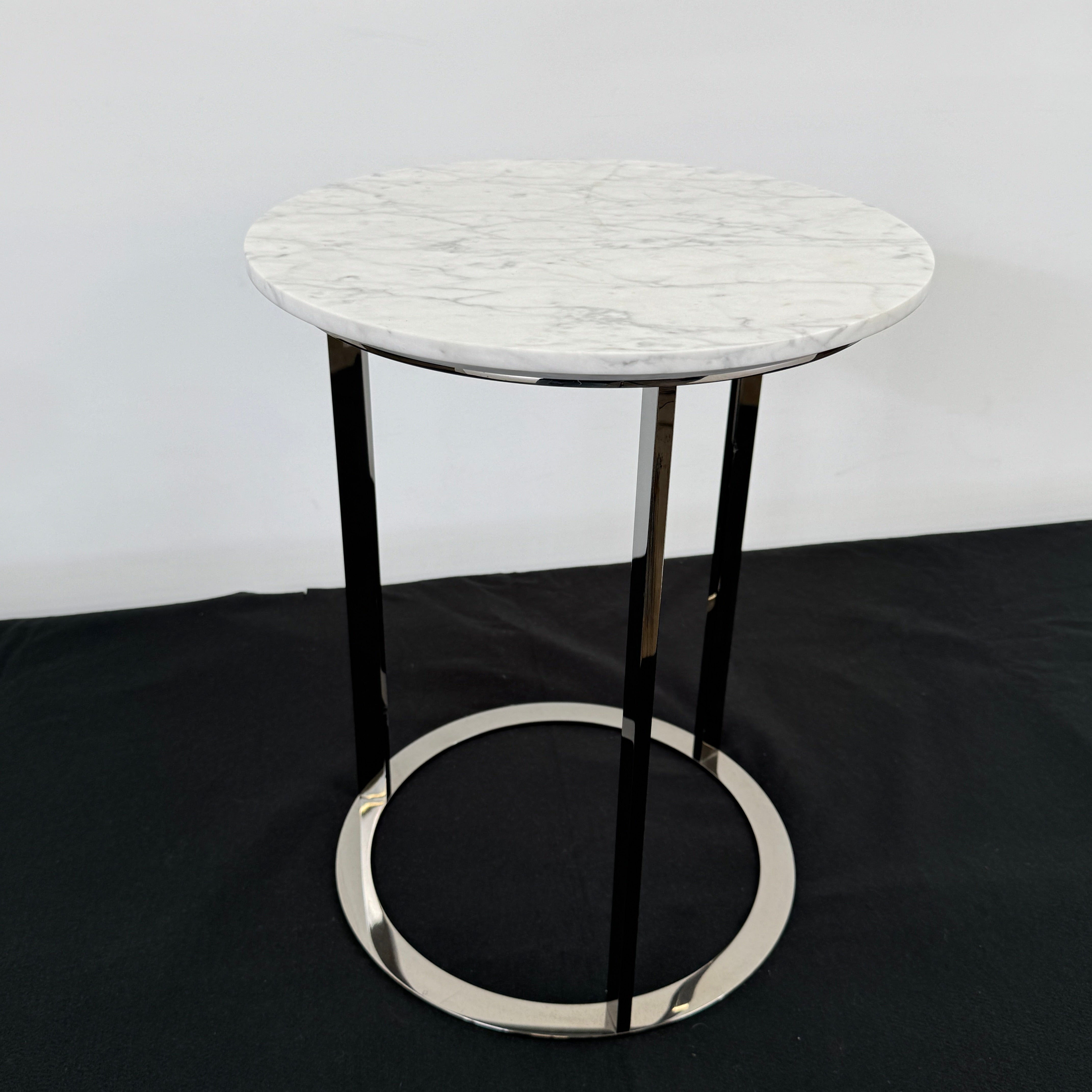 The B&B Italia Mera Accent Table features a round Carrara marble top and a three-legged metal frame with a circular base, showcasing B&B Italia's signature elegance.