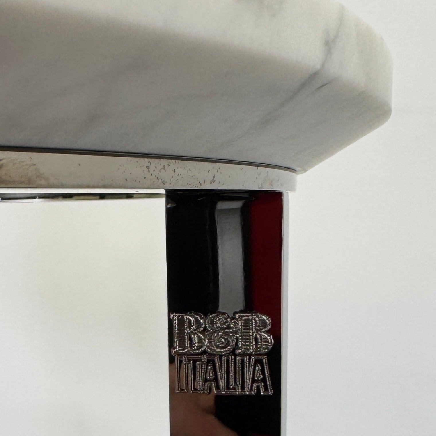 The B&B Italia Mera Accent Table features a round Carrara marble top and a three-legged metal frame with a circular base, showcasing B&B Italia's signature elegance.