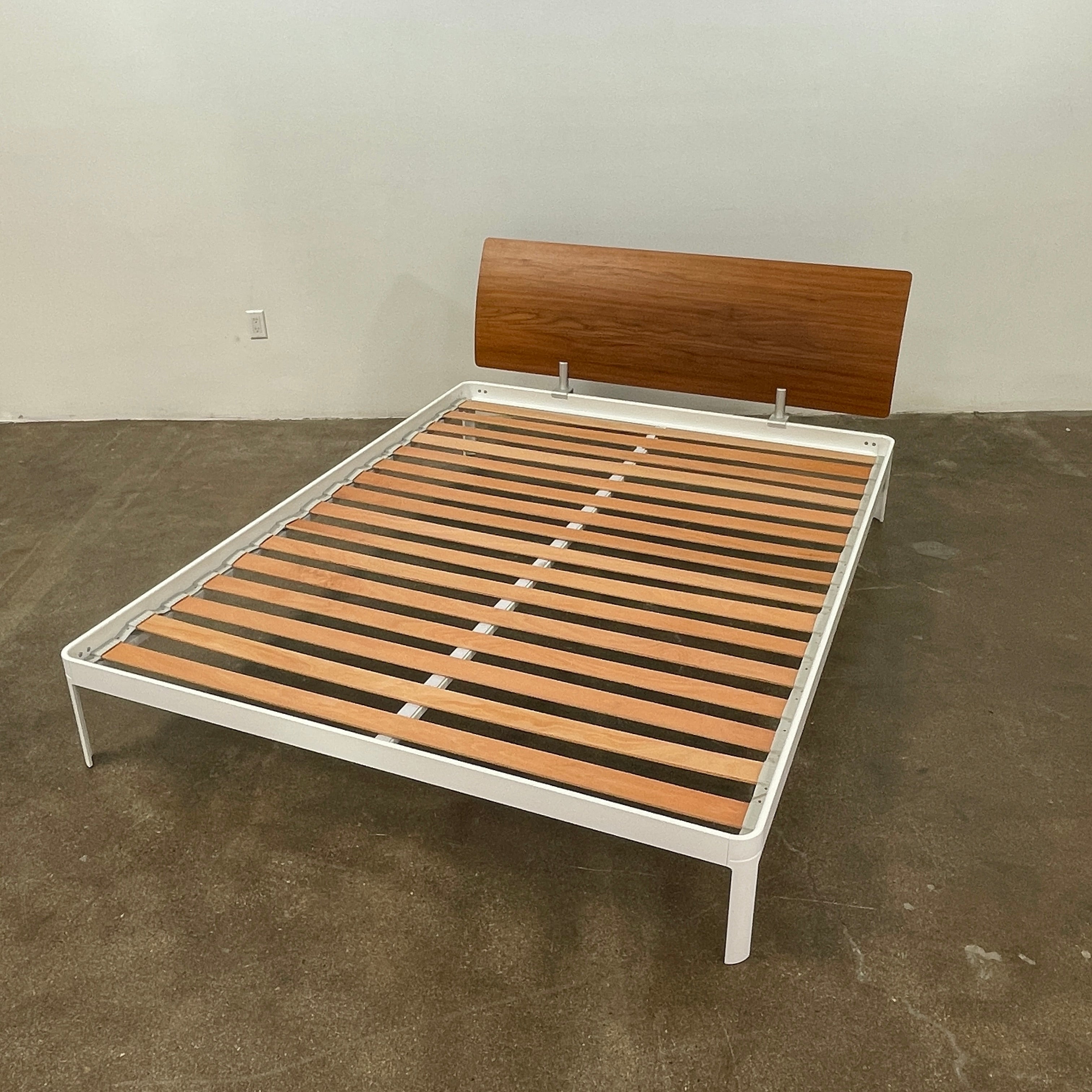 The DWR Min Queen Size Bed by Luciano Bertoncini showcases a metal frame with a sophisticated wooden headboard and slatted wooden base, elegantly placed against a plain white background.