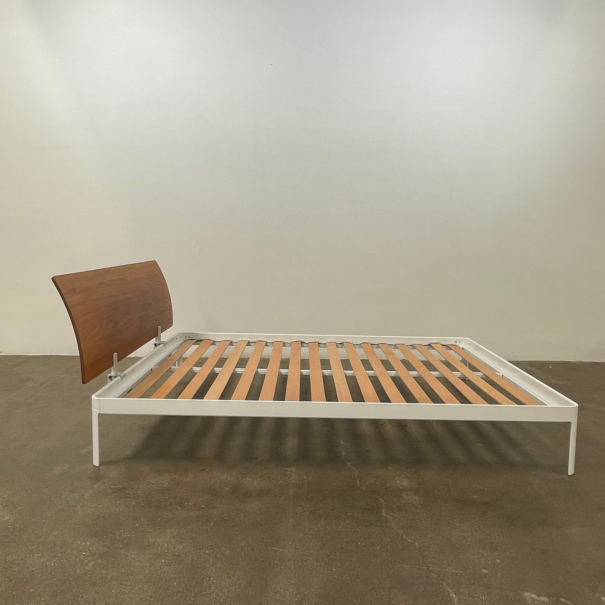 The DWR Min Queen Size Bed by Luciano Bertoncini showcases a metal frame with a sophisticated wooden headboard and slatted wooden base, elegantly placed against a plain white background.