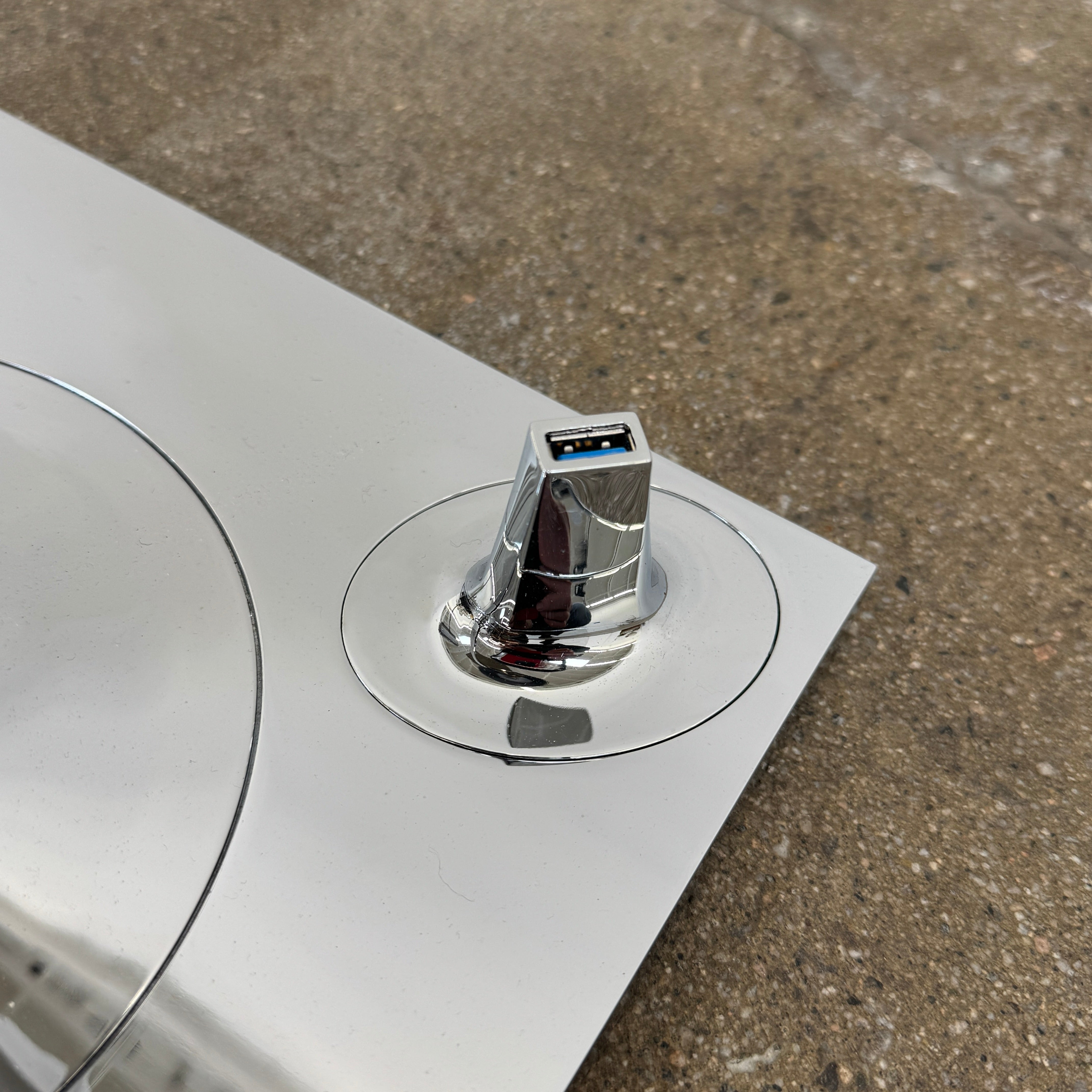 The Flos Bibliotheque Floor Lamp by Flos features a black translucent shade, metal stand, three rotating shelves, USB charging port, and square base, standing on a brown floor against a white wall.