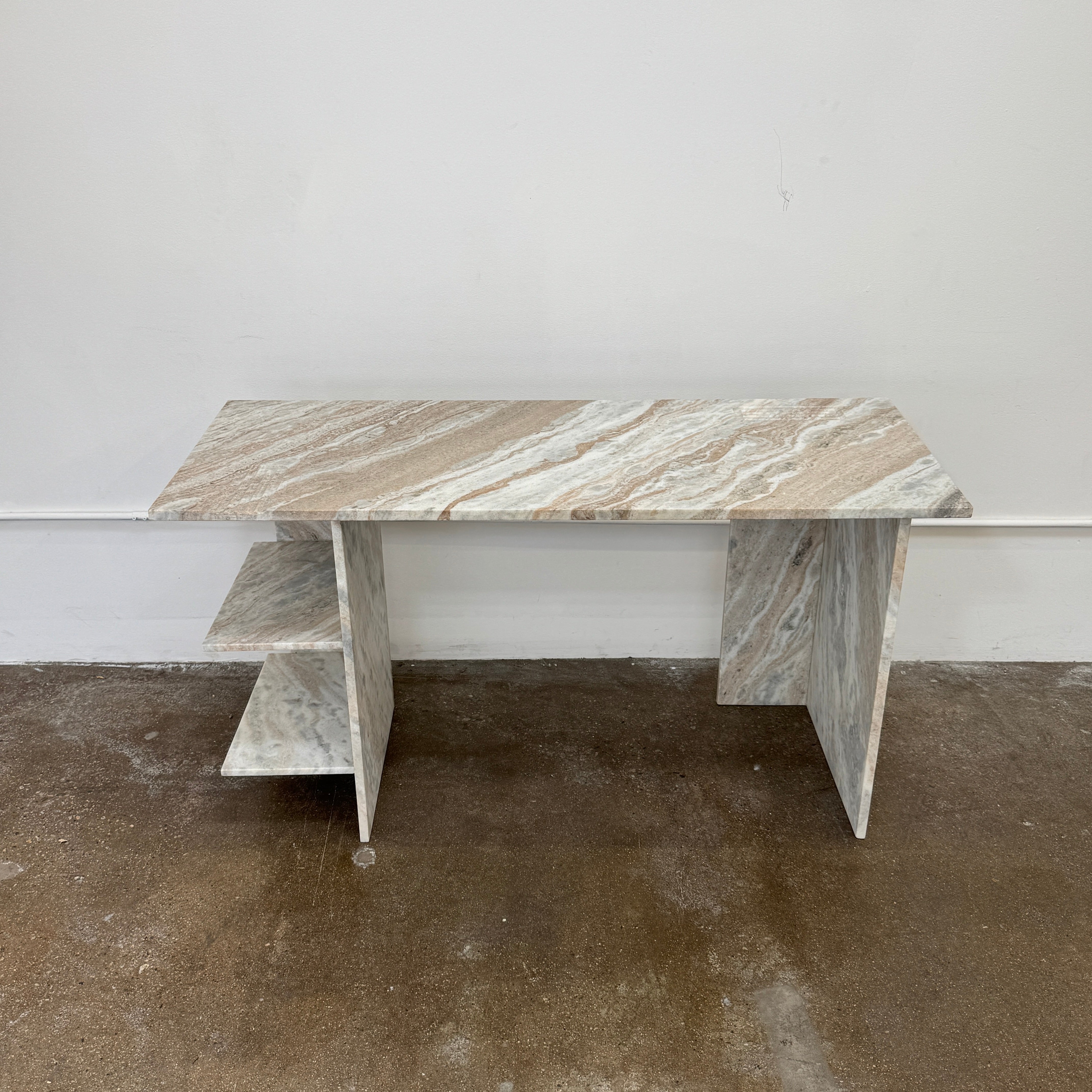 The CB2 Hera Torrento Brown Marble Desk with Shelves features two side panels and two open left corner shelves, showcasing a light gray and beige pattern inspired by Torrento brown marble.