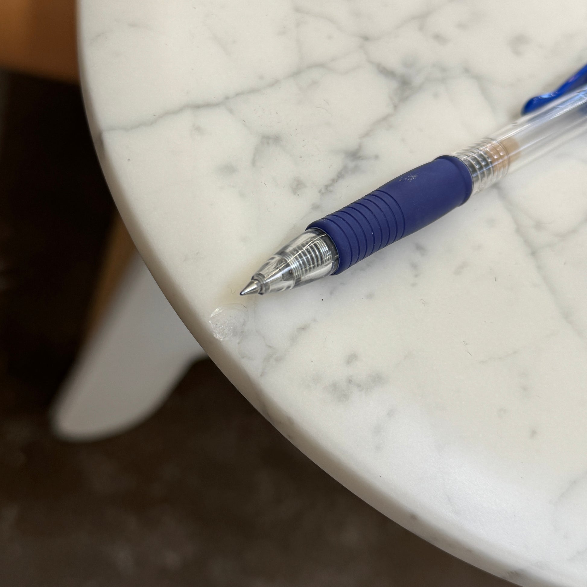 On a concrete floor against a plain white wall stands the B&B Italia Matte Carrara Marble Alex Dining Table, showcasing contemporary design with its long, rectangular form and white base, adding both style and sophistication to the space.