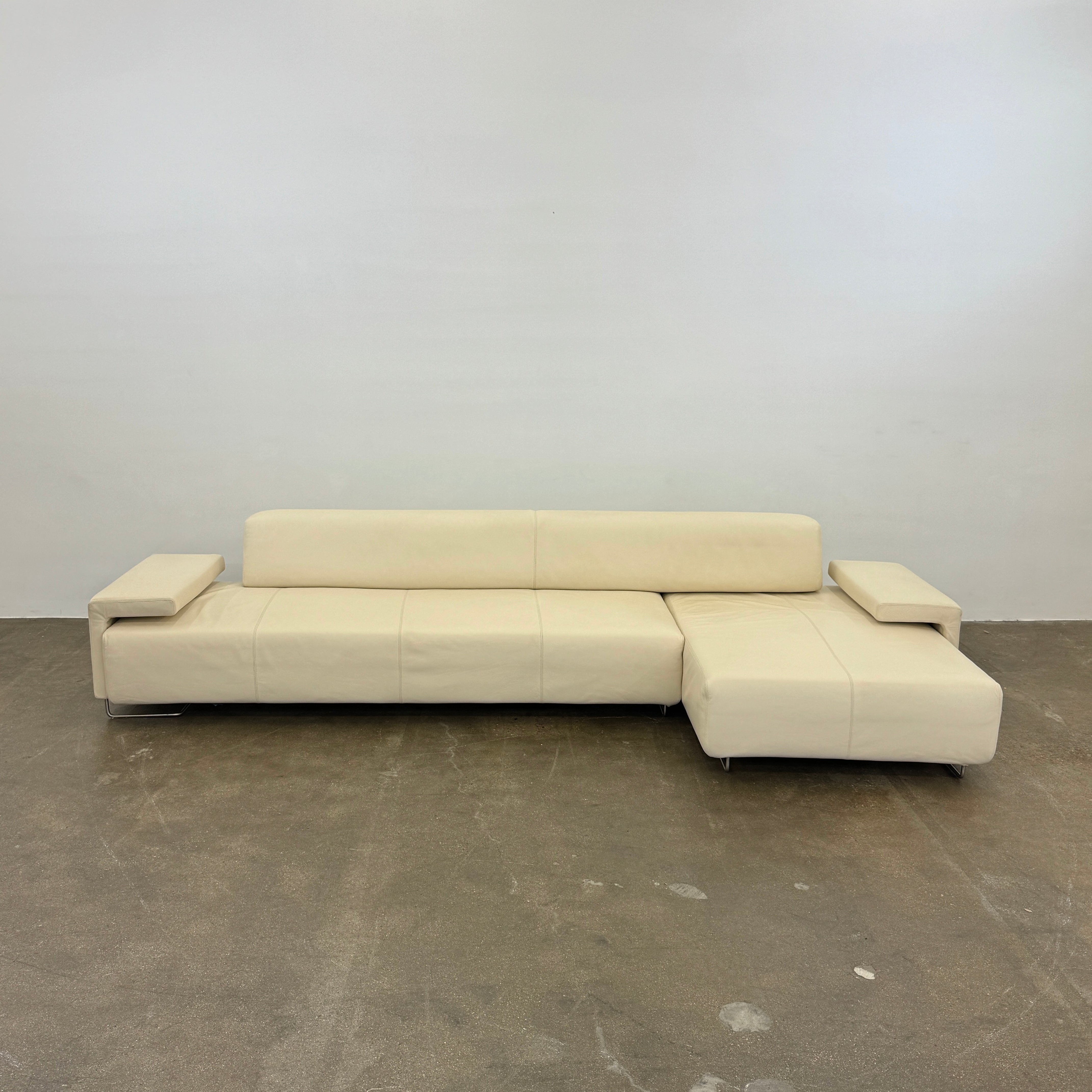 The Moroso Lowland Sectional Sofa by Moroso features beige leather, a low backrest, wide armrests, and a right-side chaise lounge inspired by Patricia Urquiola’s modern design, set against a plain white background.