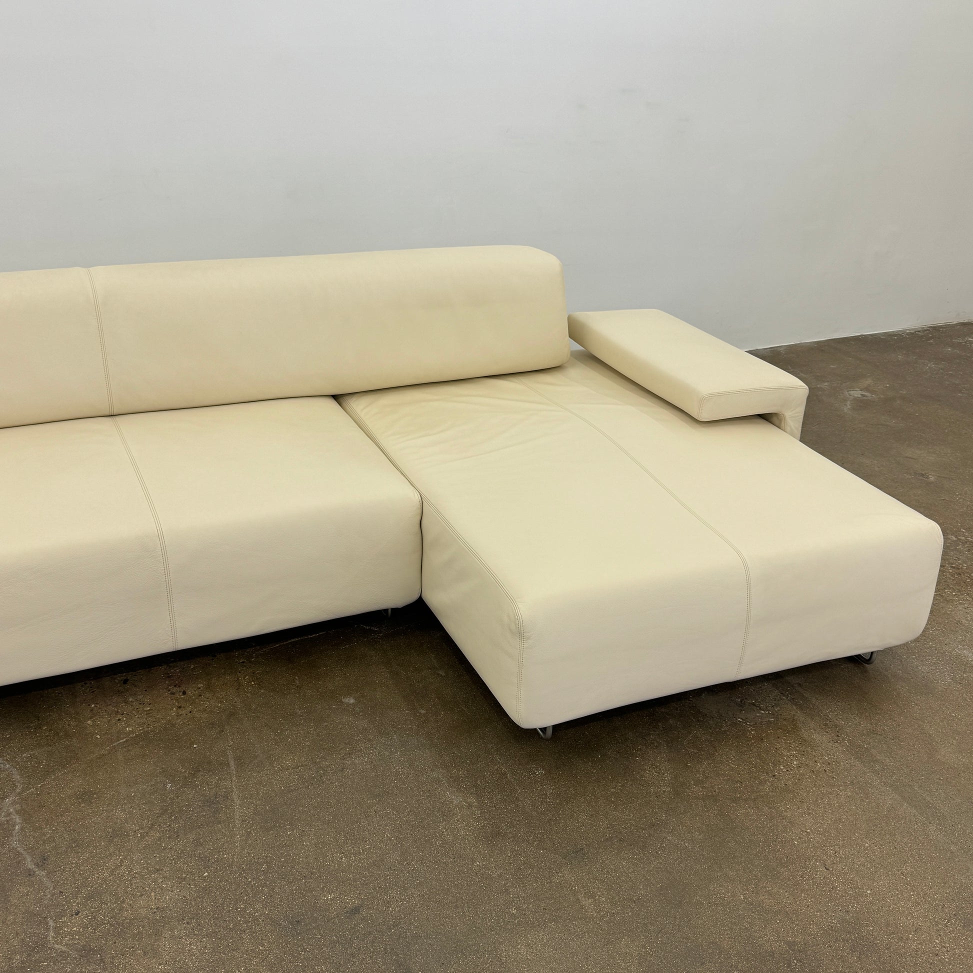 The Moroso Lowland Sectional Sofa by Moroso features beige leather, a low backrest, wide armrests, and a right-side chaise lounge inspired by Patricia Urquiola’s modern design, set against a plain white background.