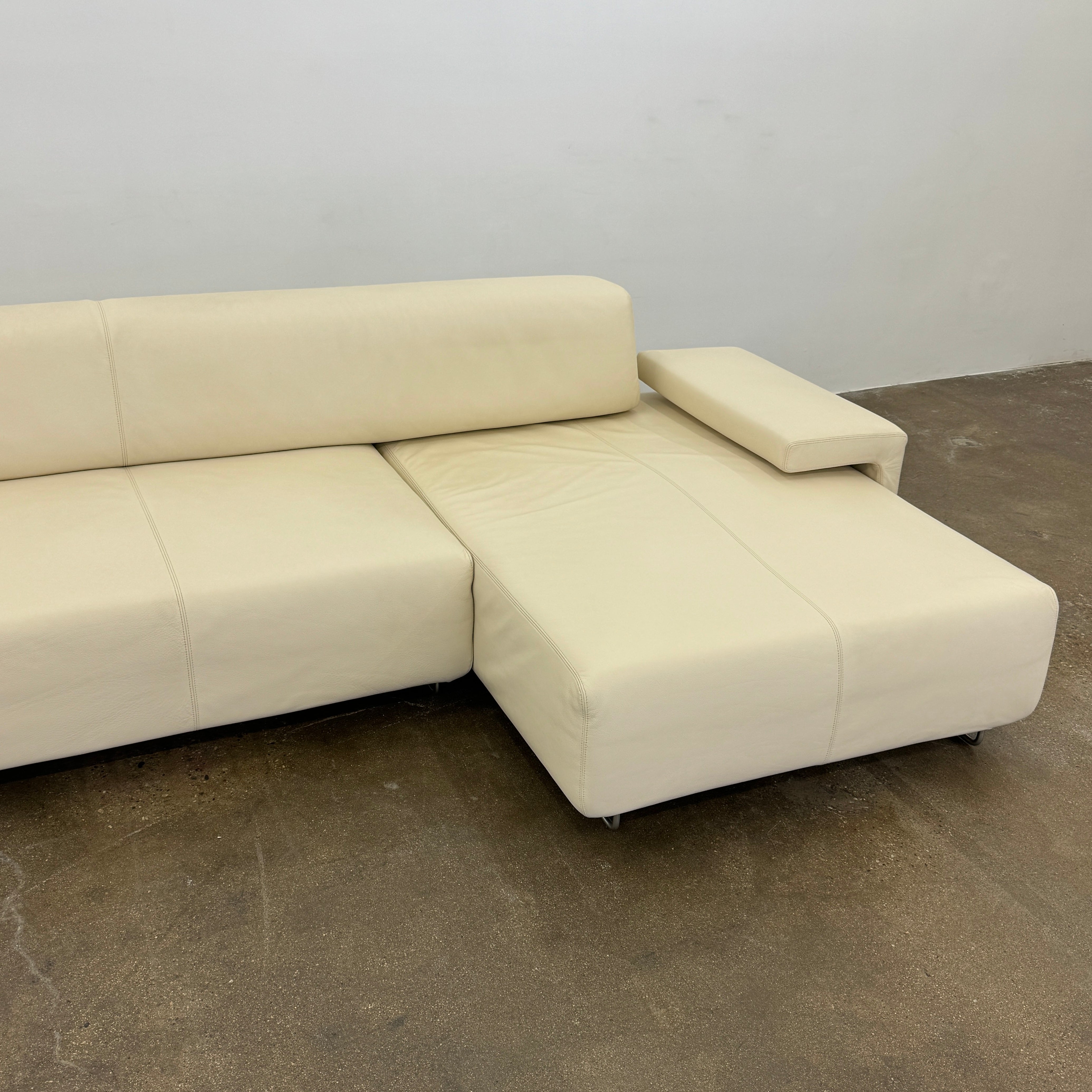 The Moroso Lowland Sectional Sofa by Moroso features beige leather, a low backrest, wide armrests, and a right-side chaise lounge inspired by Patricia Urquiola’s modern design, set against a plain white background.