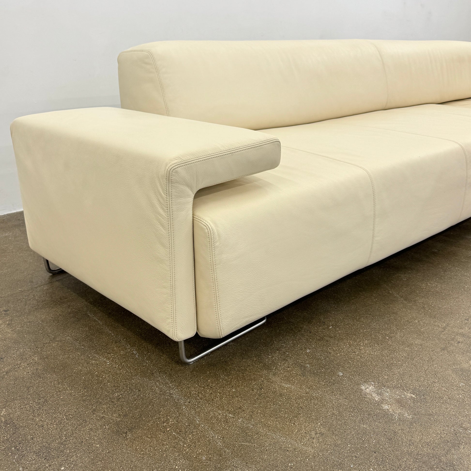 The Moroso Lowland Sectional Sofa by Moroso features beige leather, a low backrest, wide armrests, and a right-side chaise lounge inspired by Patricia Urquiola’s modern design, set against a plain white background.