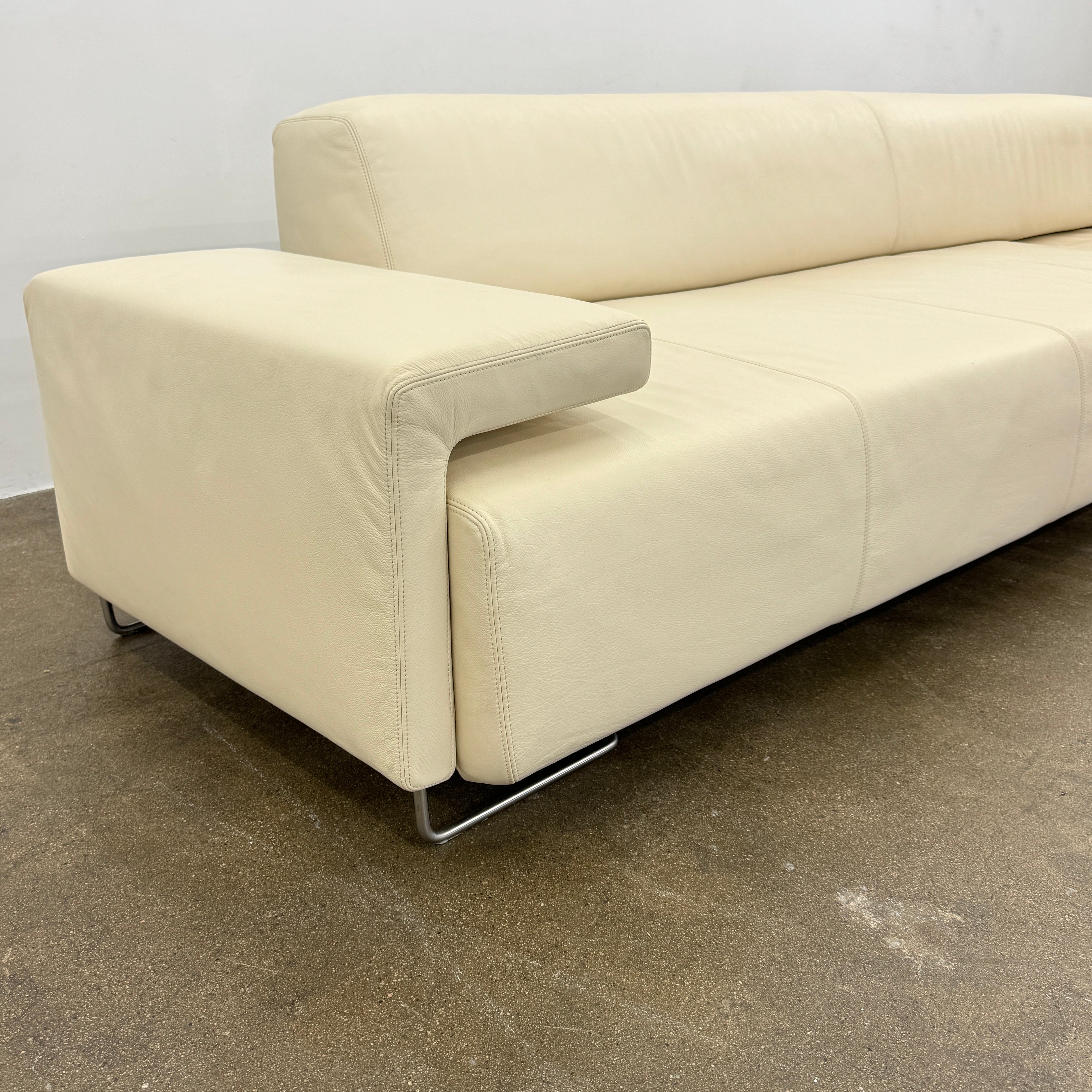 The Moroso Lowland Sectional Sofa by Moroso features beige leather, a low backrest, wide armrests, and a right-side chaise lounge inspired by Patricia Urquiola’s modern design, set against a plain white background.