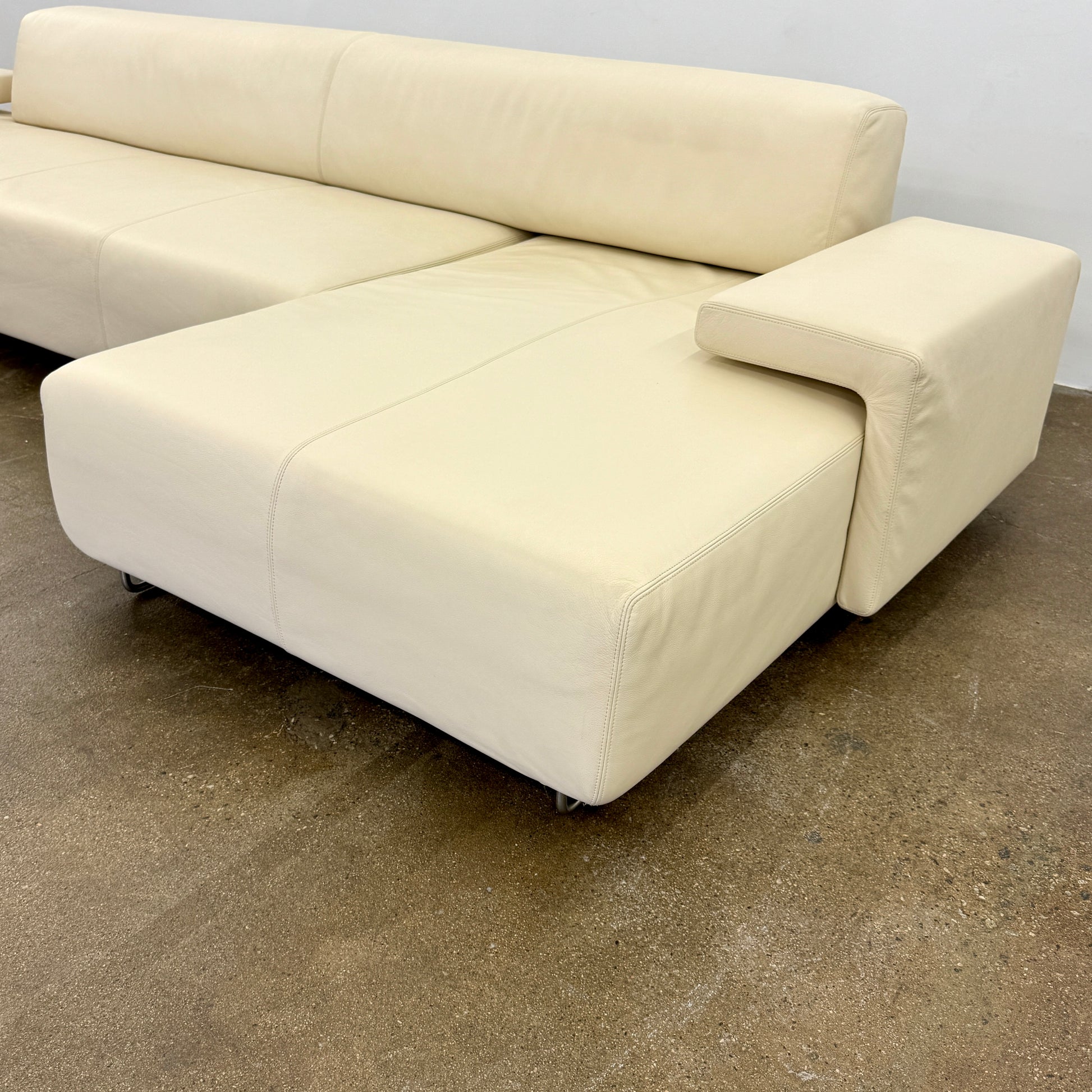 The Moroso Lowland Sectional Sofa by Moroso features beige leather, a low backrest, wide armrests, and a right-side chaise lounge inspired by Patricia Urquiola’s modern design, set against a plain white background.
