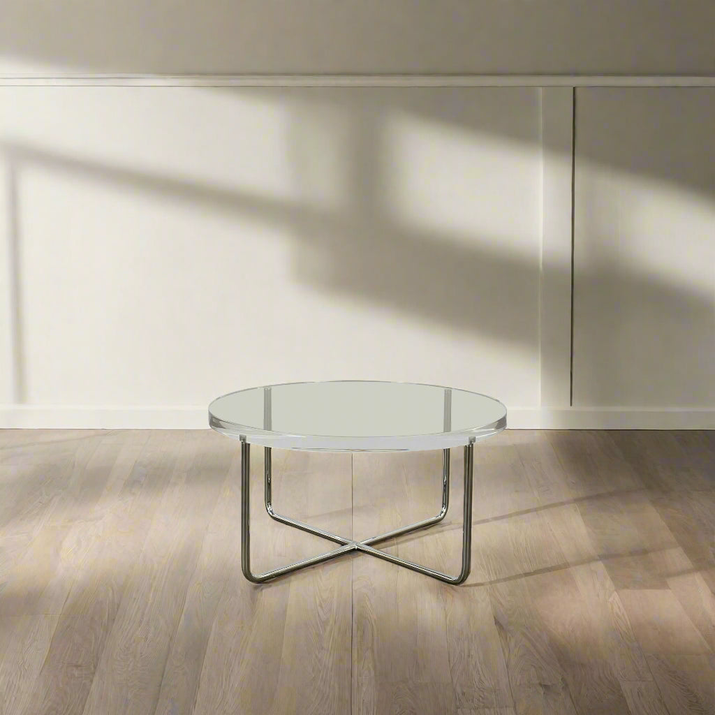 The Minotti Lucite Accent Table boasts a round glass top with a chrome metal frame and crossed base, capturing the Italian elegance synonymous with Minotti's design.