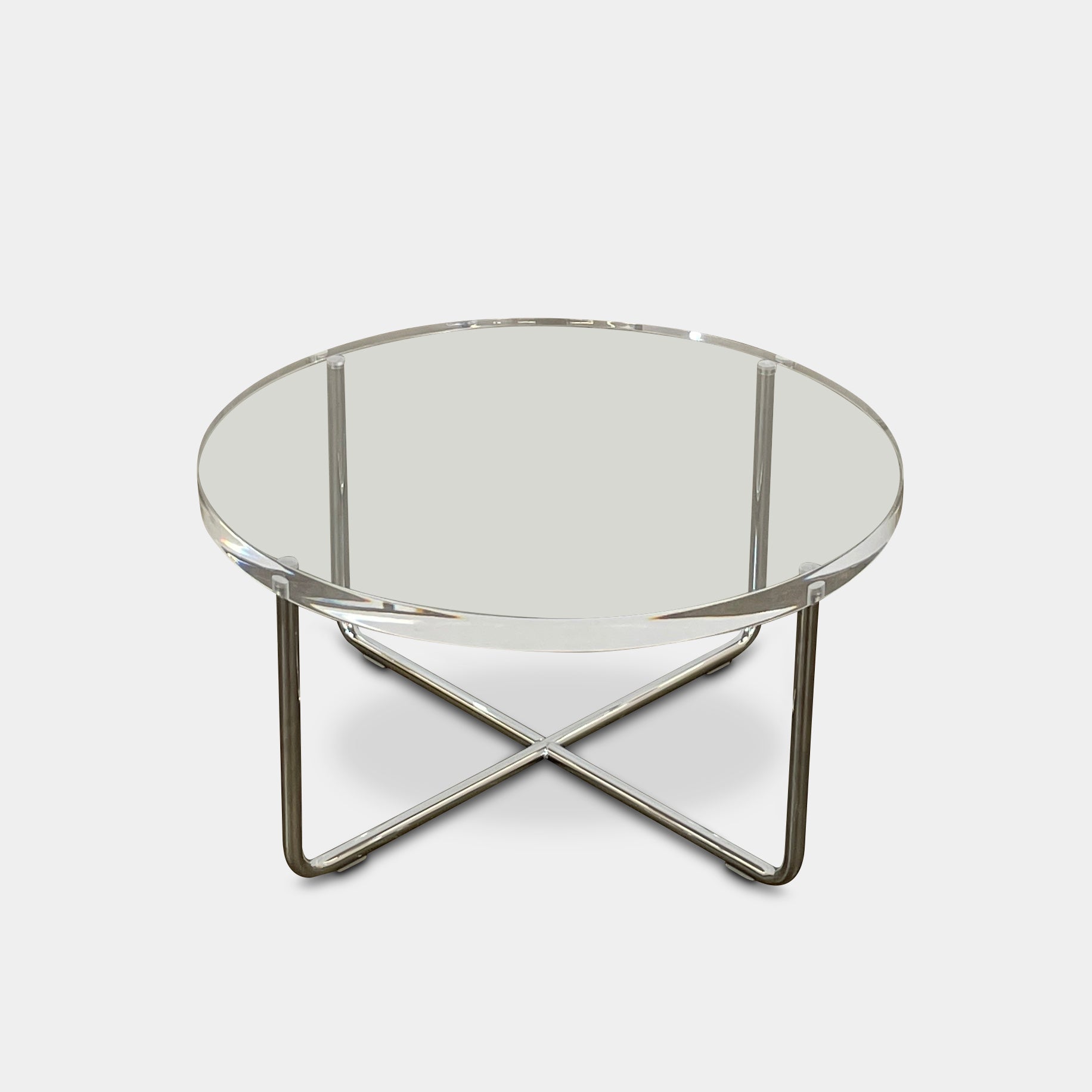 The Minotti Lucite Accent Table boasts a round glass top with a chrome metal frame and crossed base, capturing the Italian elegance synonymous with Minotti's design.