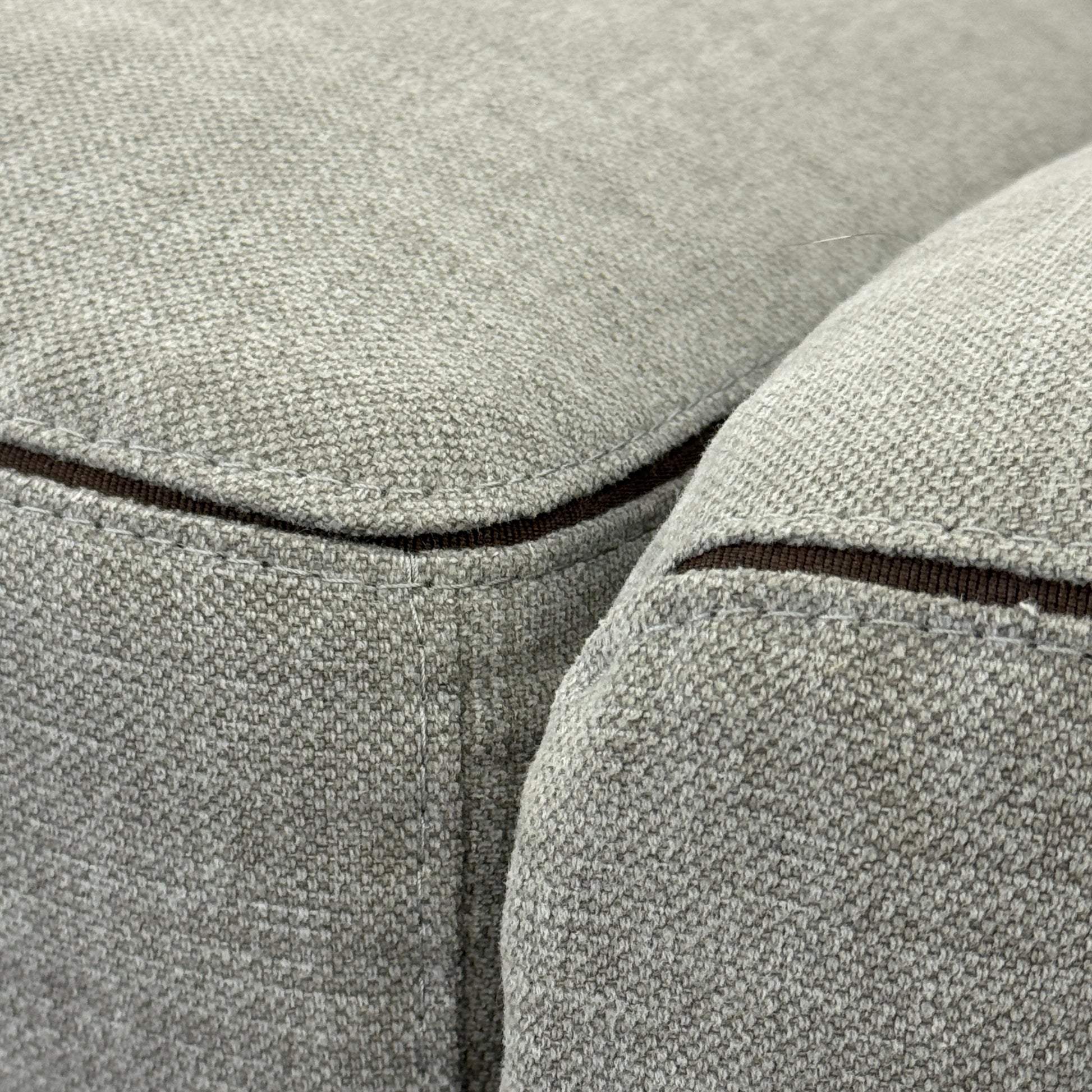 A modern Cassina Scighera Sofa by Cassina, in light gray with two matching square cushions, is placed on a bare concrete floor against a plain white wall.