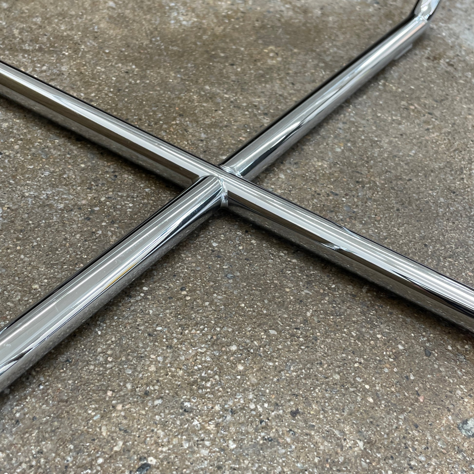 The Minotti Lucite Accent Table boasts a round glass top with a chrome metal frame and crossed base, capturing the Italian elegance synonymous with Minotti's design.