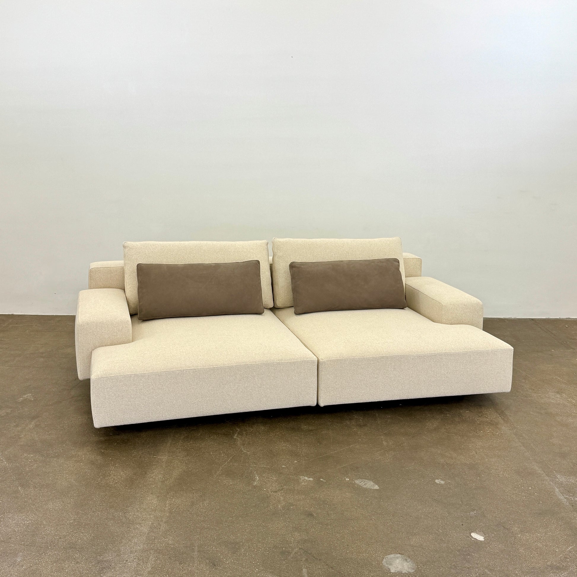 The Molteni & C Marteen Sofa is a modern beige sofa with wide armrests and two rectangular brown back cushions, featuring linen blend upholstery. Shown from the front on a white background.