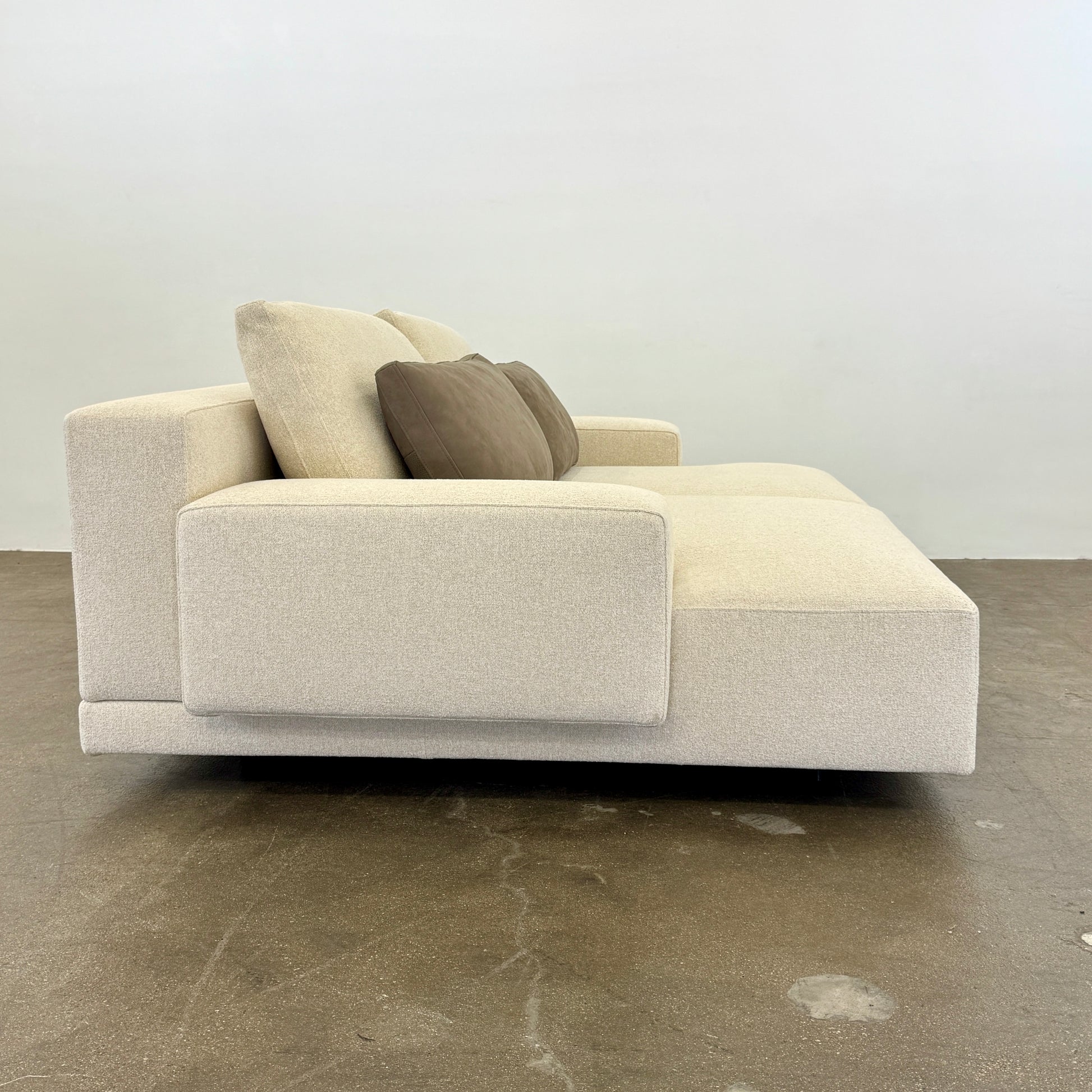 The Molteni & C Marteen Sofa is a modern beige sofa with wide armrests and two rectangular brown back cushions, featuring linen blend upholstery. Shown from the front on a white background.