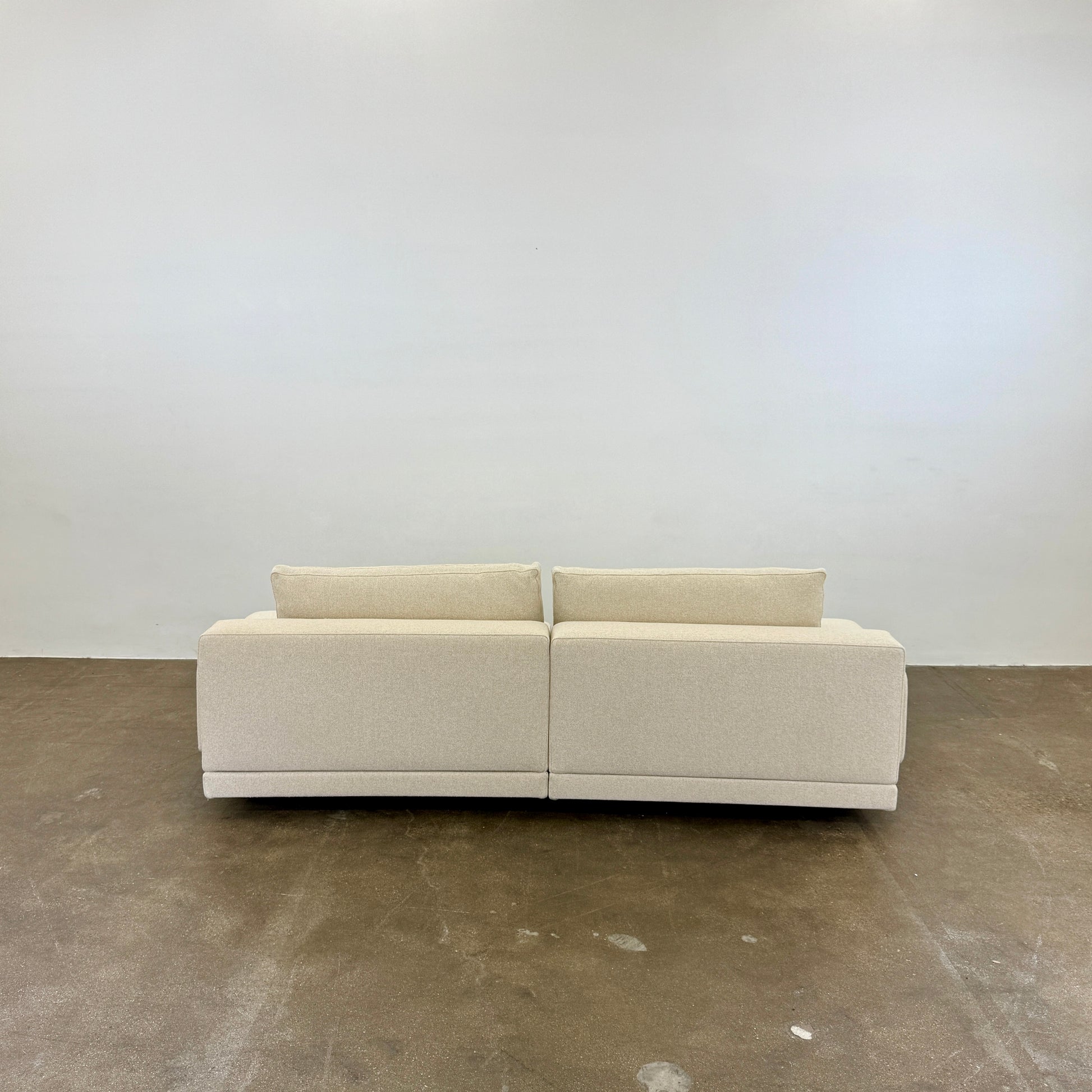 The Molteni & C Marteen Sofa is a modern beige sofa with wide armrests and two rectangular brown back cushions, featuring linen blend upholstery. Shown from the front on a white background.