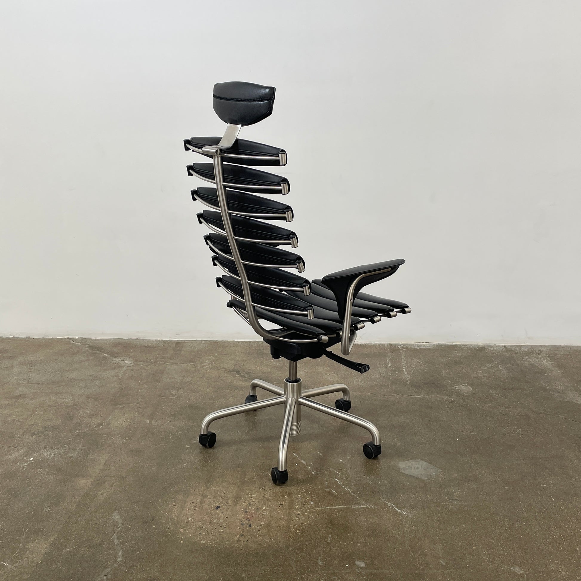 The De Sede DS-2100 High-Backed Executive Office Chair features a segmented black leather backrest, adjustable armrests, headrest, and a sturdy metal swivel base with five caster wheels.