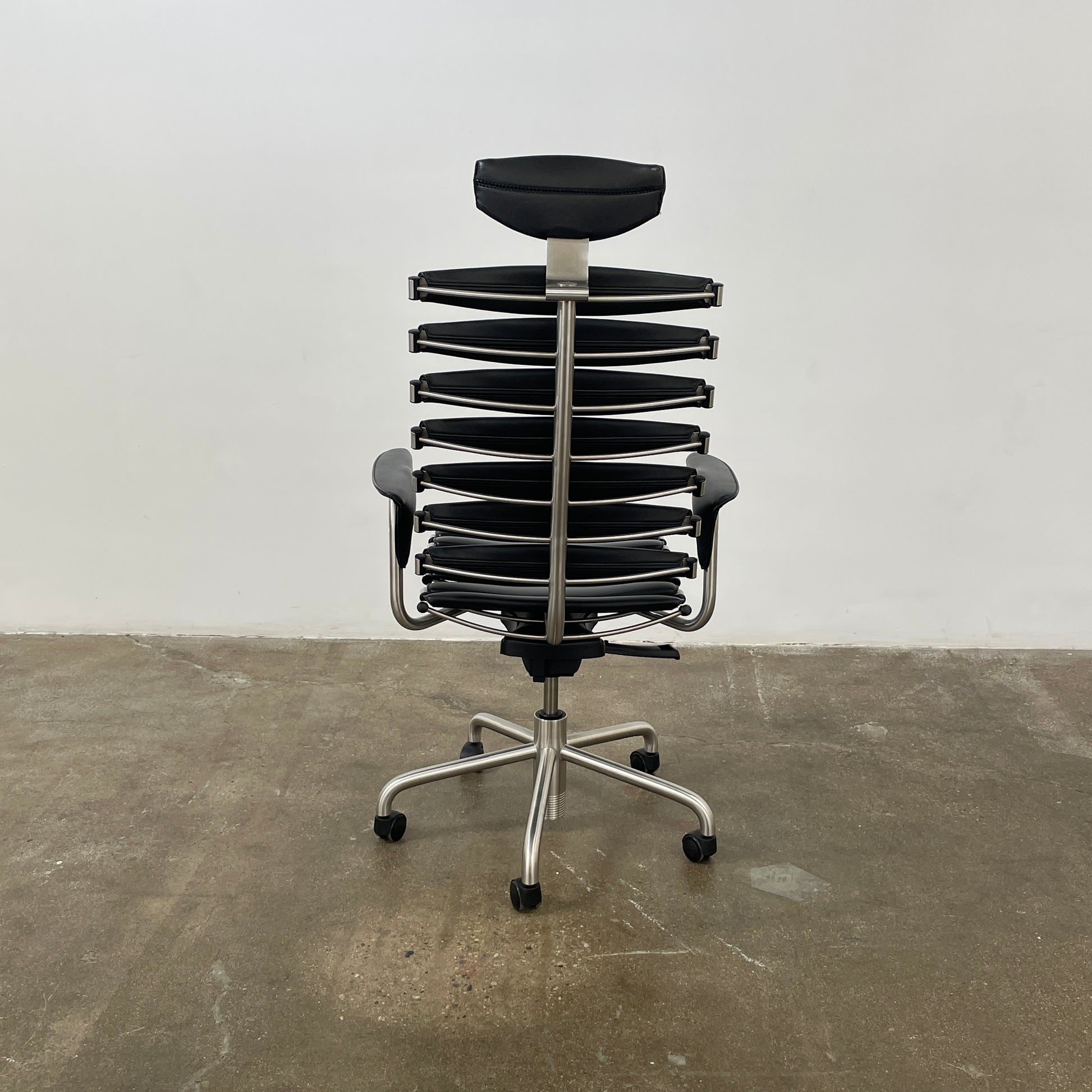 The De Sede DS-2100 High-Backed Executive Office Chair features a segmented black leather backrest, adjustable armrests, headrest, and a sturdy metal swivel base with five caster wheels.