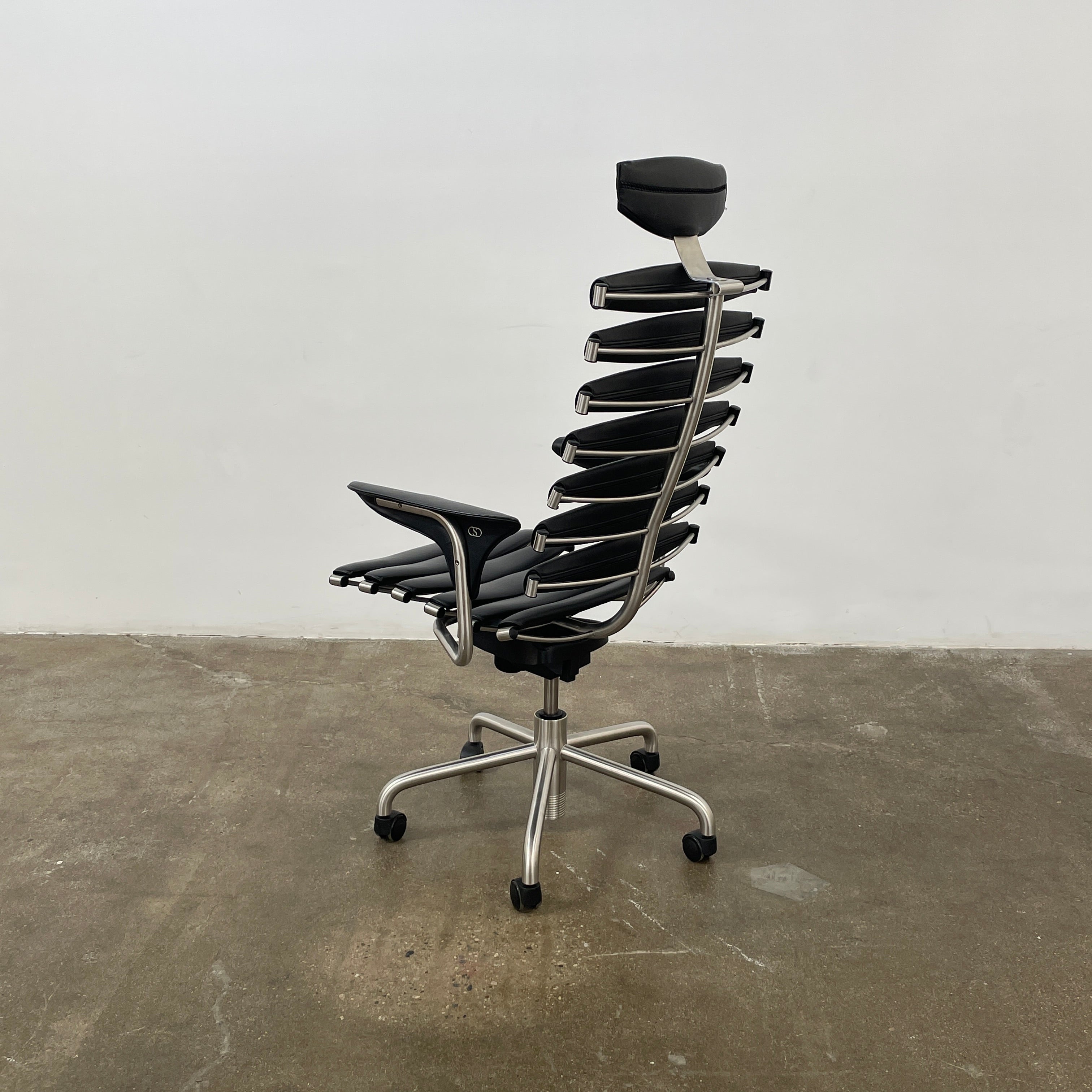 The De Sede DS-2100 High-Backed Executive Office Chair features a segmented black leather backrest, adjustable armrests, headrest, and a sturdy metal swivel base with five caster wheels.