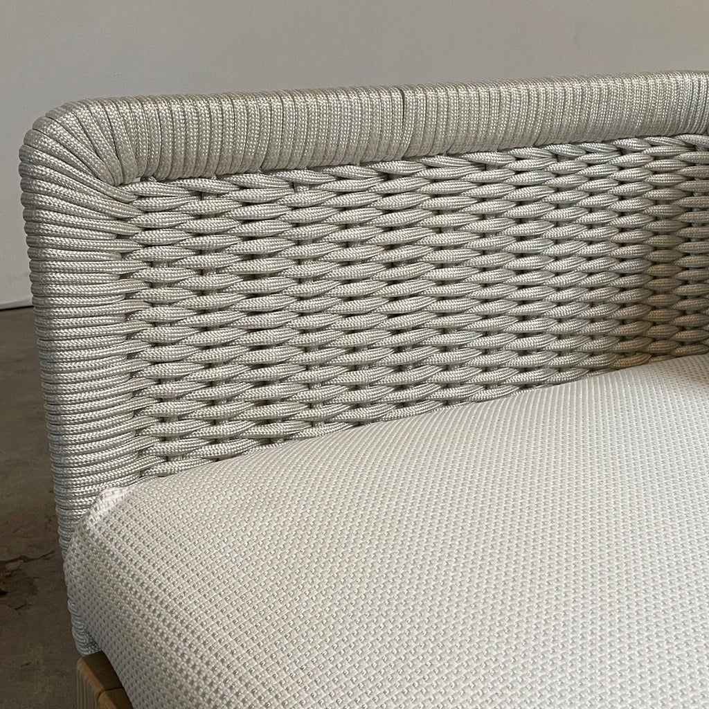 The Paola Lenti Sabi Outdoor Lounge Chair by Paola Lenti features a wicker design and includes a white cushion. It is showcased against a white background.
