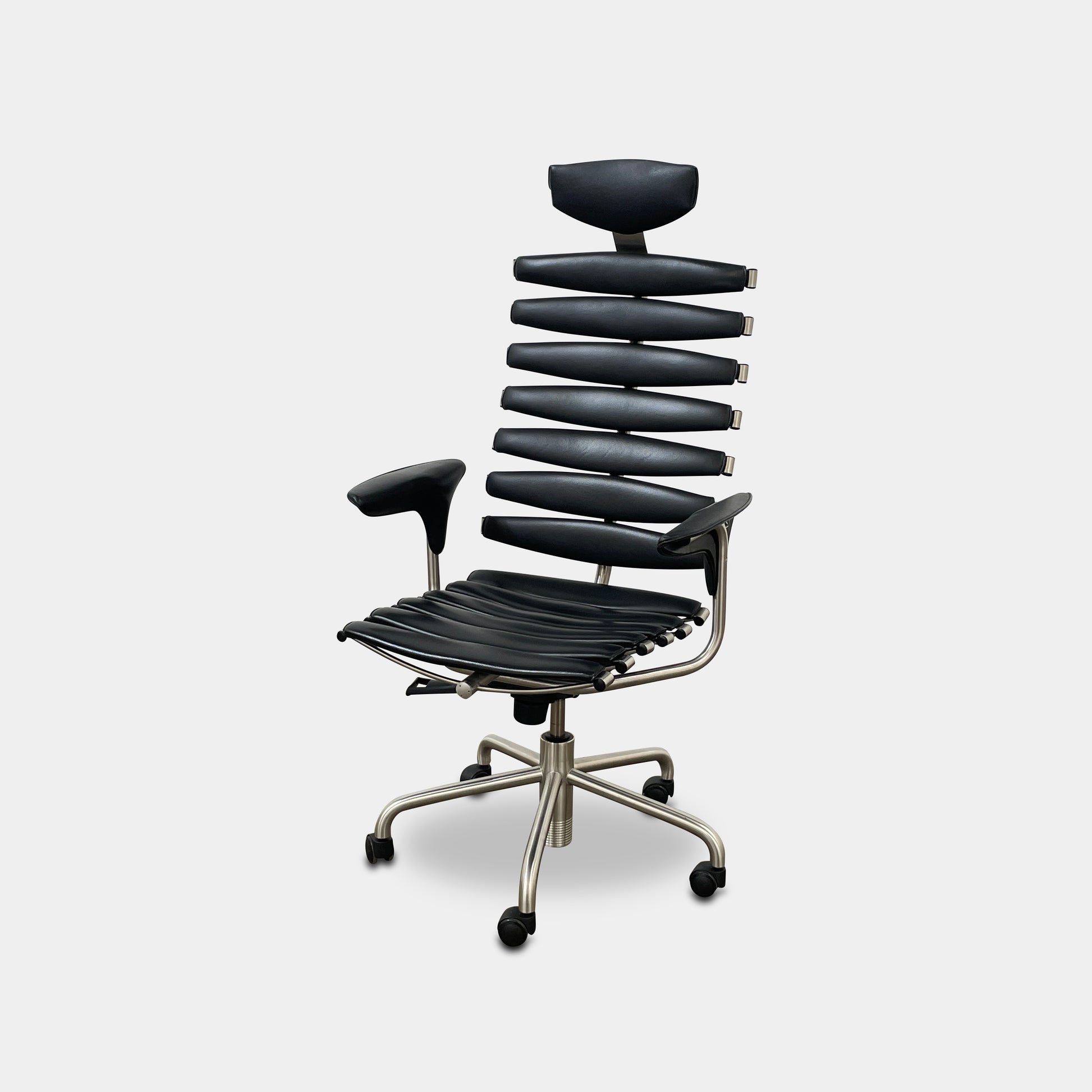 The De Sede DS-2100 High-Backed Executive Office Chair features a segmented black leather backrest, adjustable armrests, headrest, and a sturdy metal swivel base with five caster wheels.