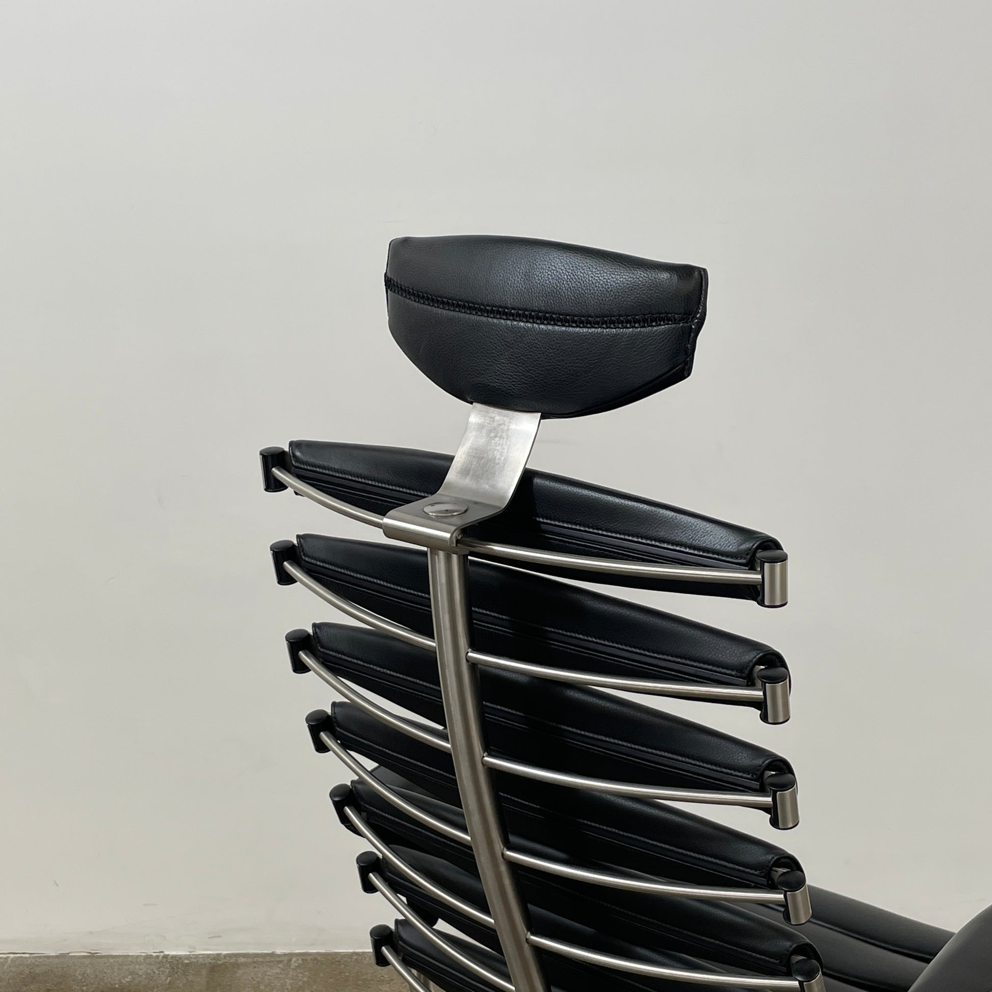 The De Sede DS-2100 High-Backed Executive Office Chair features a segmented black leather backrest, adjustable armrests, headrest, and a sturdy metal swivel base with five caster wheels.