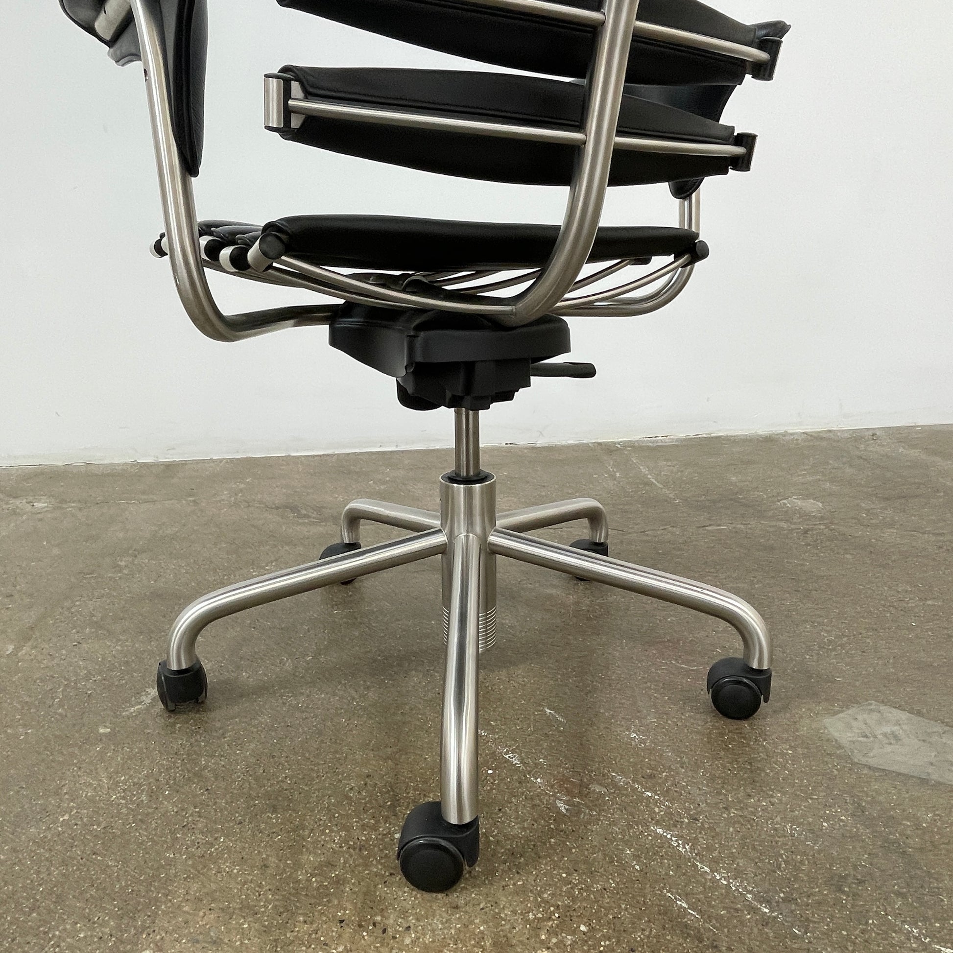 The De Sede DS-2100 High-Backed Executive Office Chair features a segmented black leather backrest, adjustable armrests, headrest, and a sturdy metal swivel base with five caster wheels.