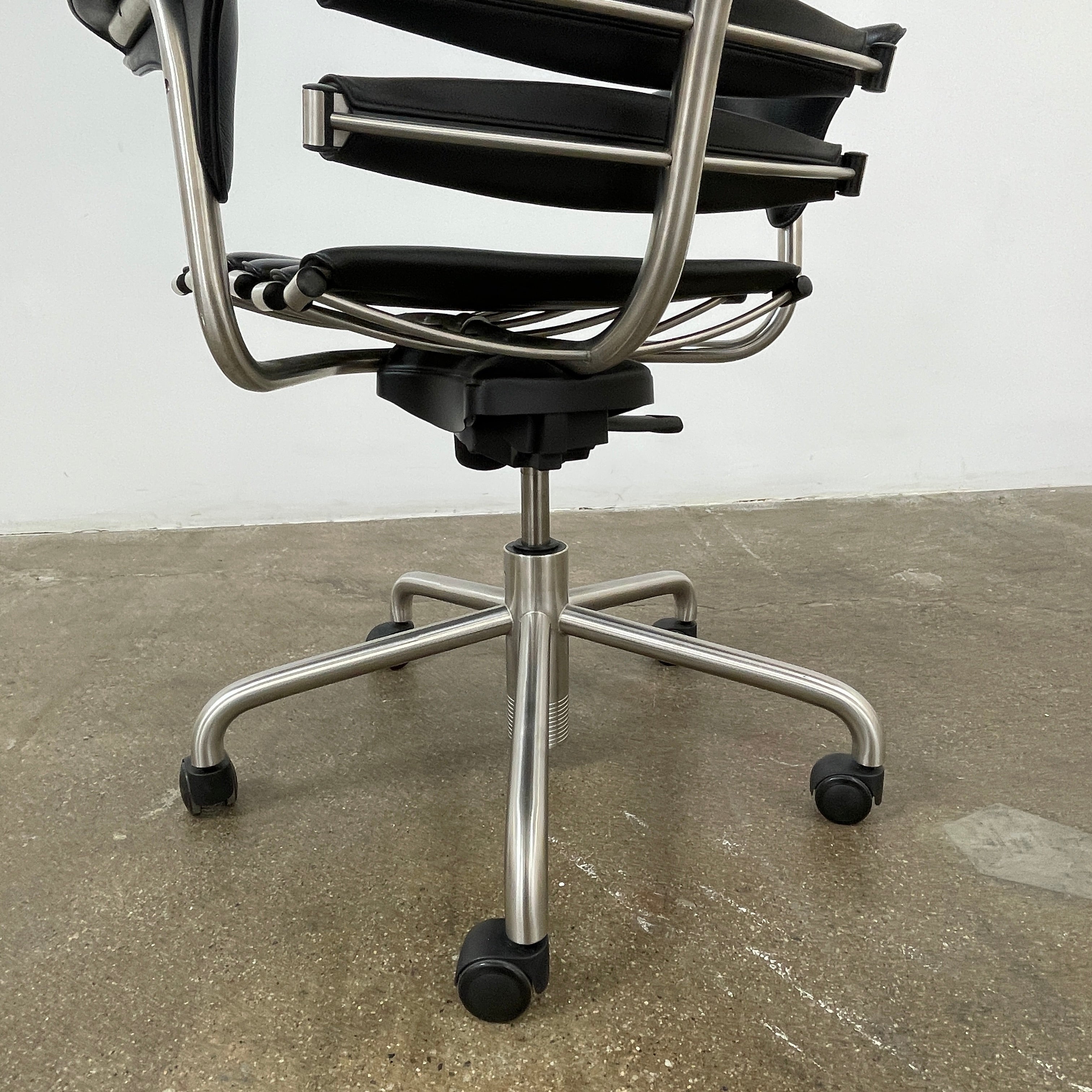 The De Sede DS-2100 High-Backed Executive Office Chair features a segmented black leather backrest, adjustable armrests, headrest, and a sturdy metal swivel base with five caster wheels.