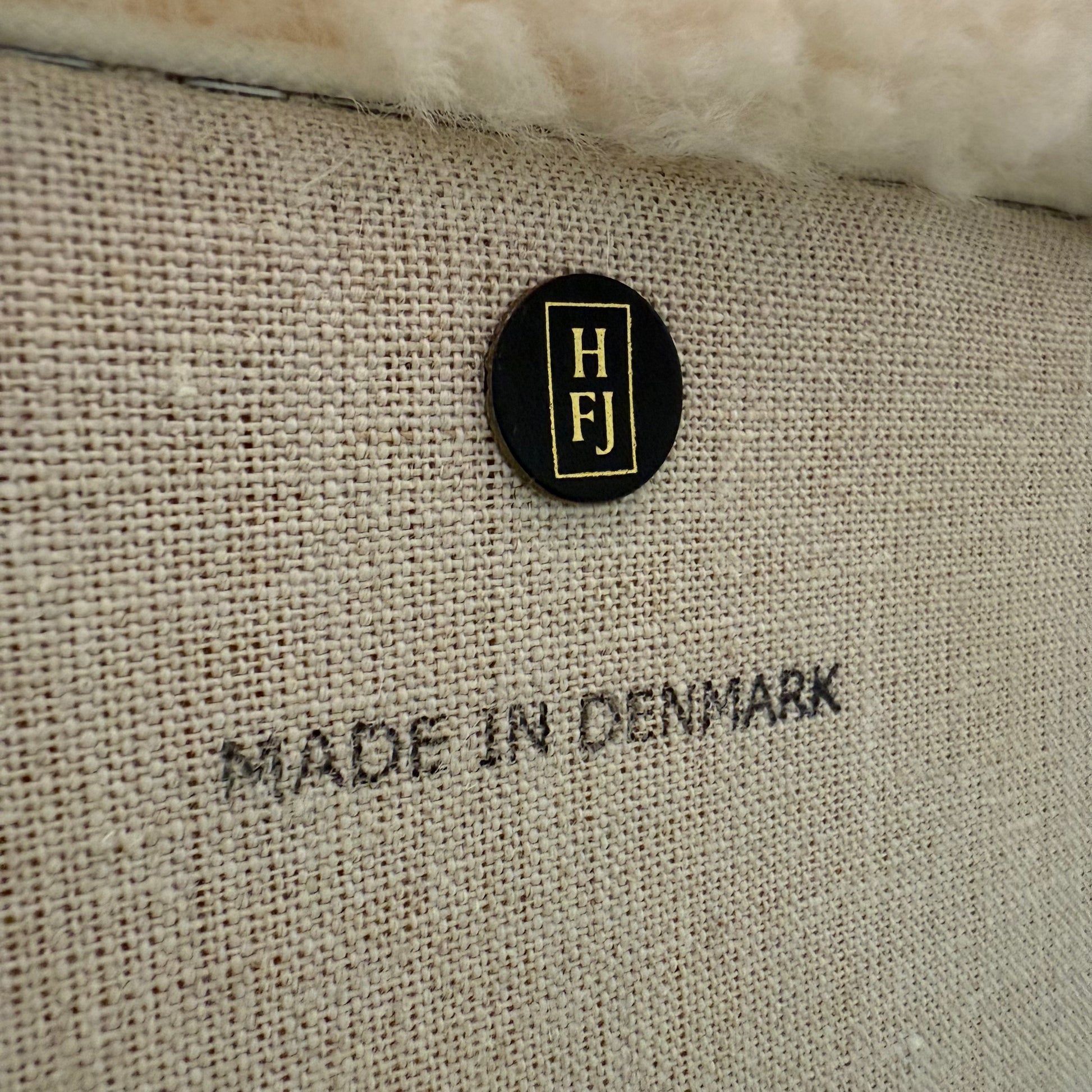 The House of Finn Juhl Finn Juhl Pelican Chair Sheepskin, with curved armrests and wooden legs, is displayed against a plain white background.