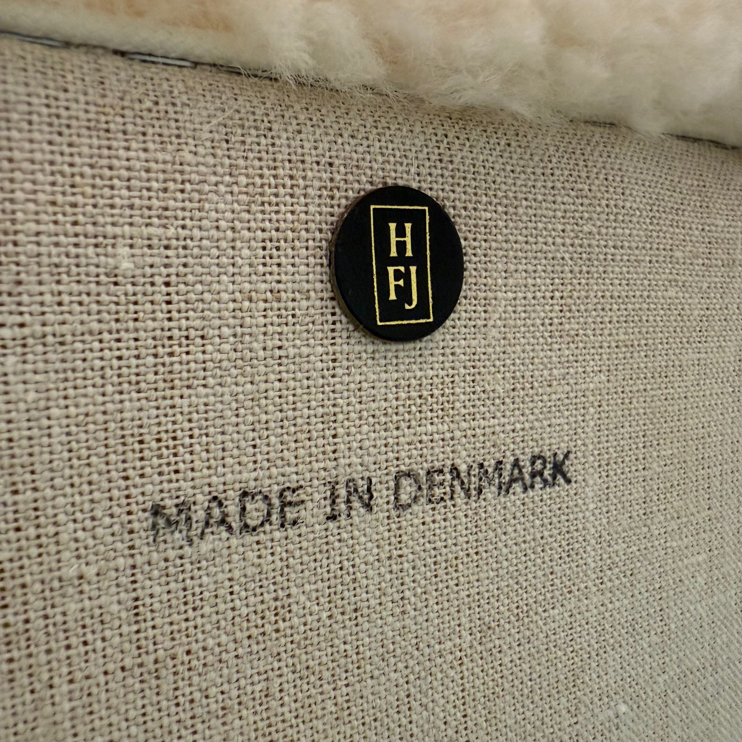 The House of Finn Juhl Finn Juhl Pelican Chair Sheepskin, with curved armrests and wooden legs, is displayed against a plain white background.