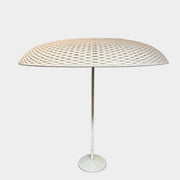 A Paola Lenti Mogambo Parasol on a white stand, designed by Paola Lenti.