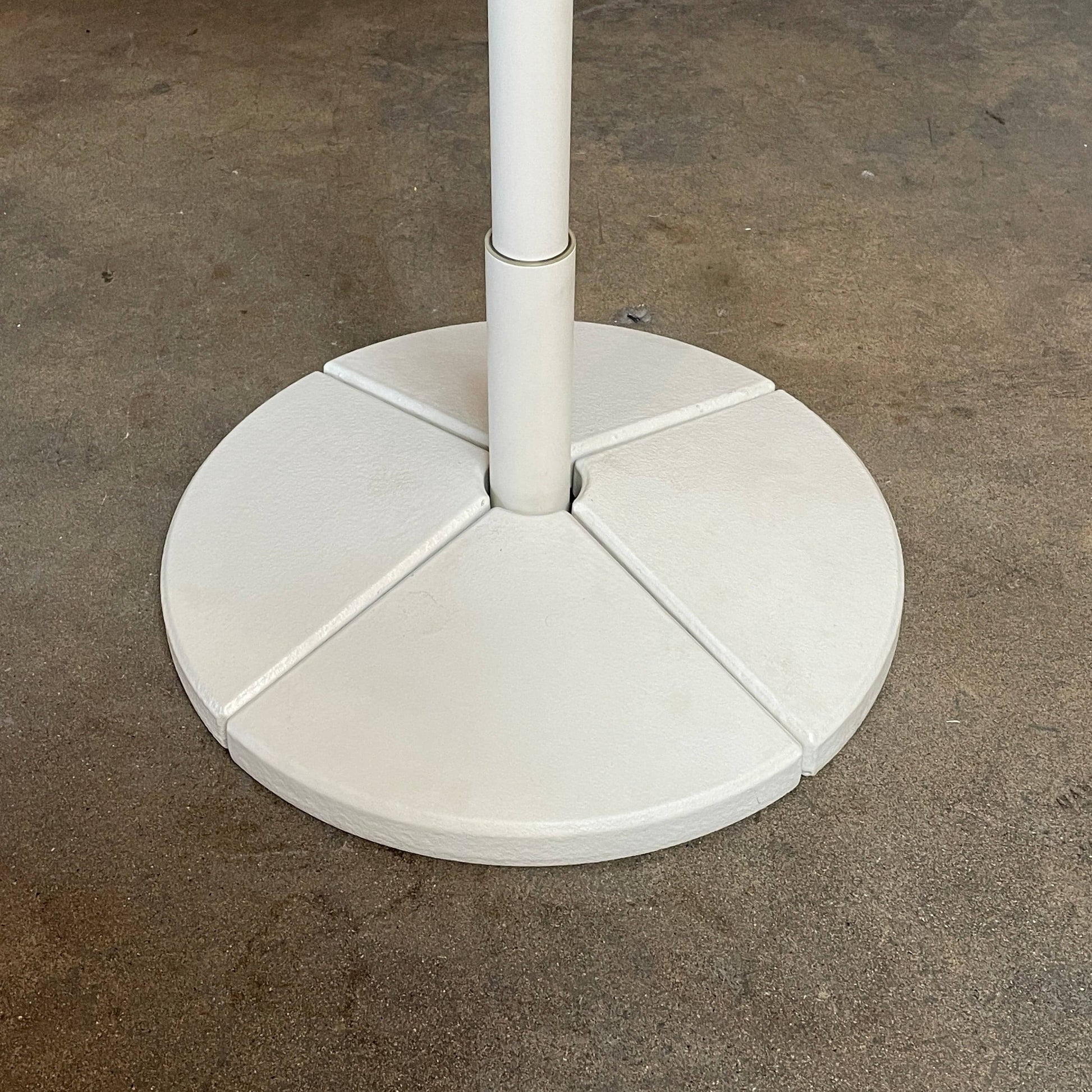 A Paola Lenti Mogambo Parasol on a white stand, designed by Paola Lenti.