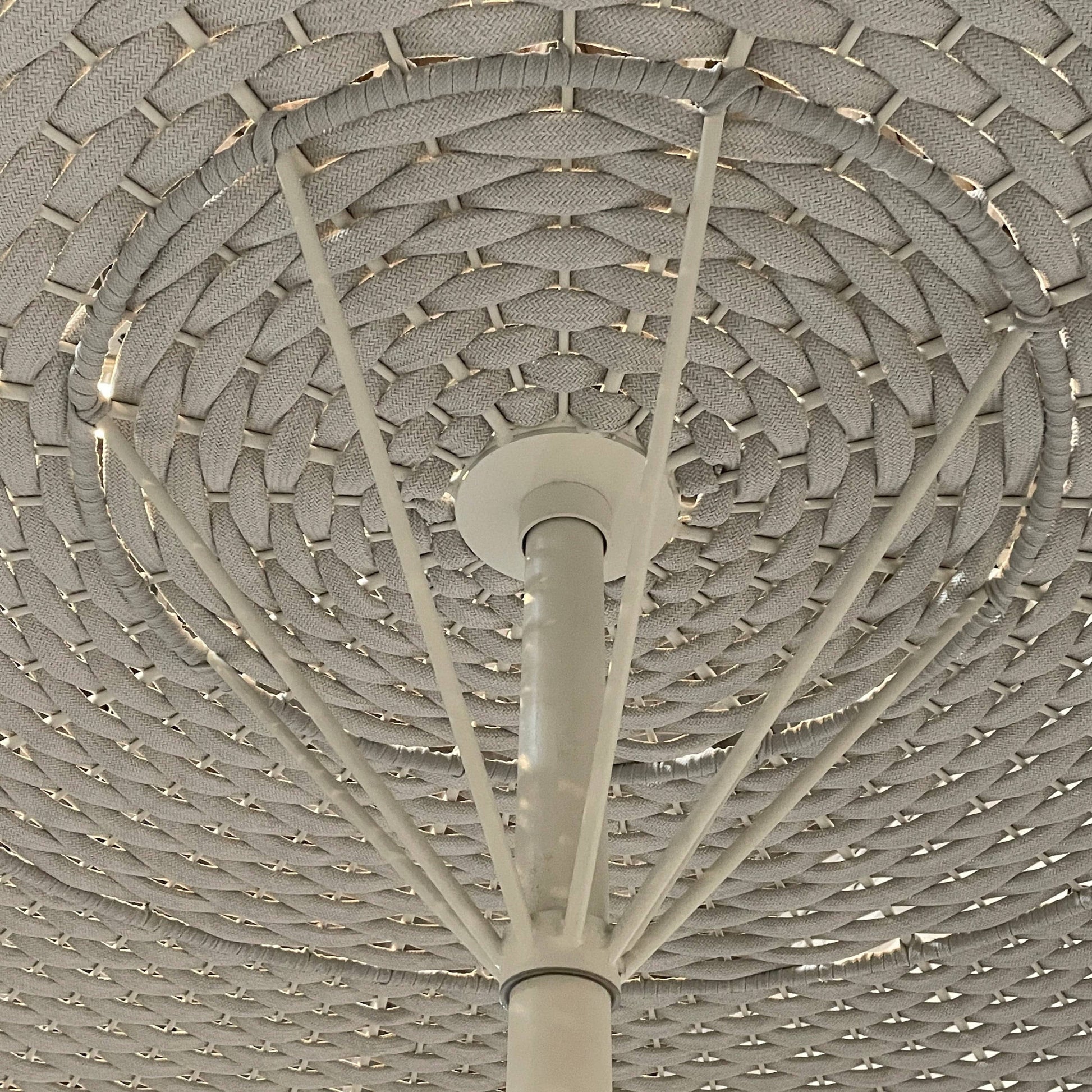 A Paola Lenti Mogambo Parasol on a white stand, designed by Paola Lenti.
