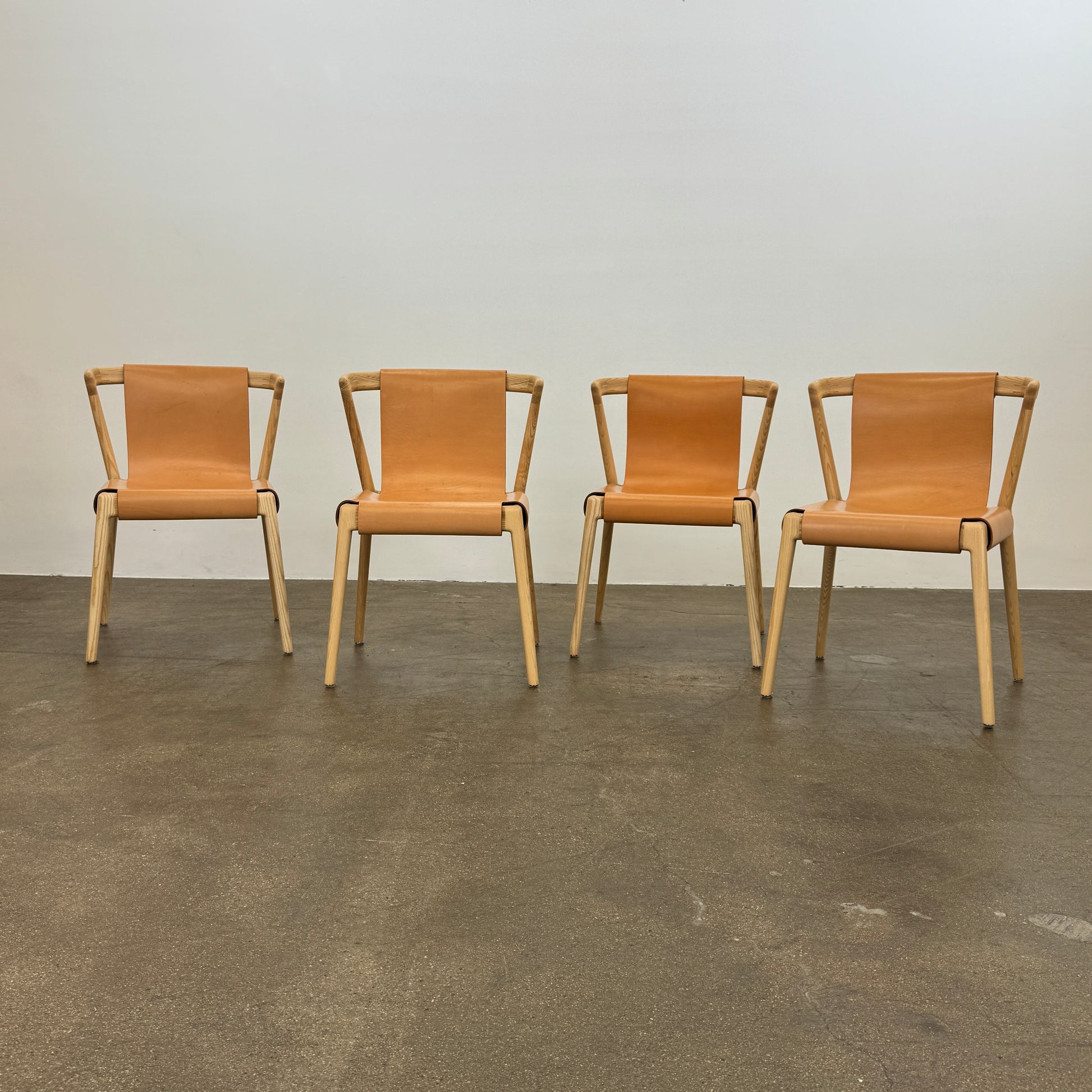 The Tom Feraday Pieman Dining Chair Set of 4 features Hydrowood timber frames and light brown leather seats and backs, offering a perfect blend of elegance and comfort. All four chairs are shown in two rows against a plain white background.