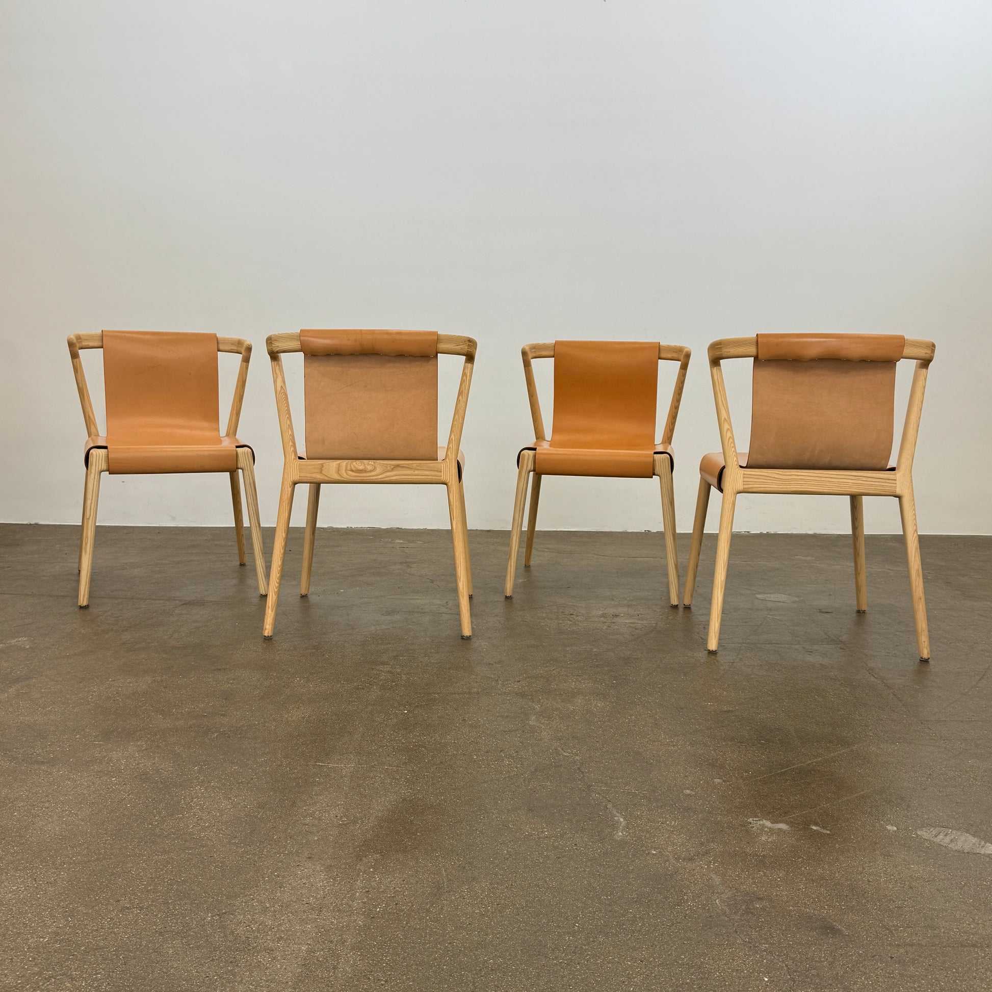 The Tom Feraday Pieman Dining Chair Set of 4 features Hydrowood timber frames and light brown leather seats and backs, offering a perfect blend of elegance and comfort. All four chairs are shown in two rows against a plain white background.