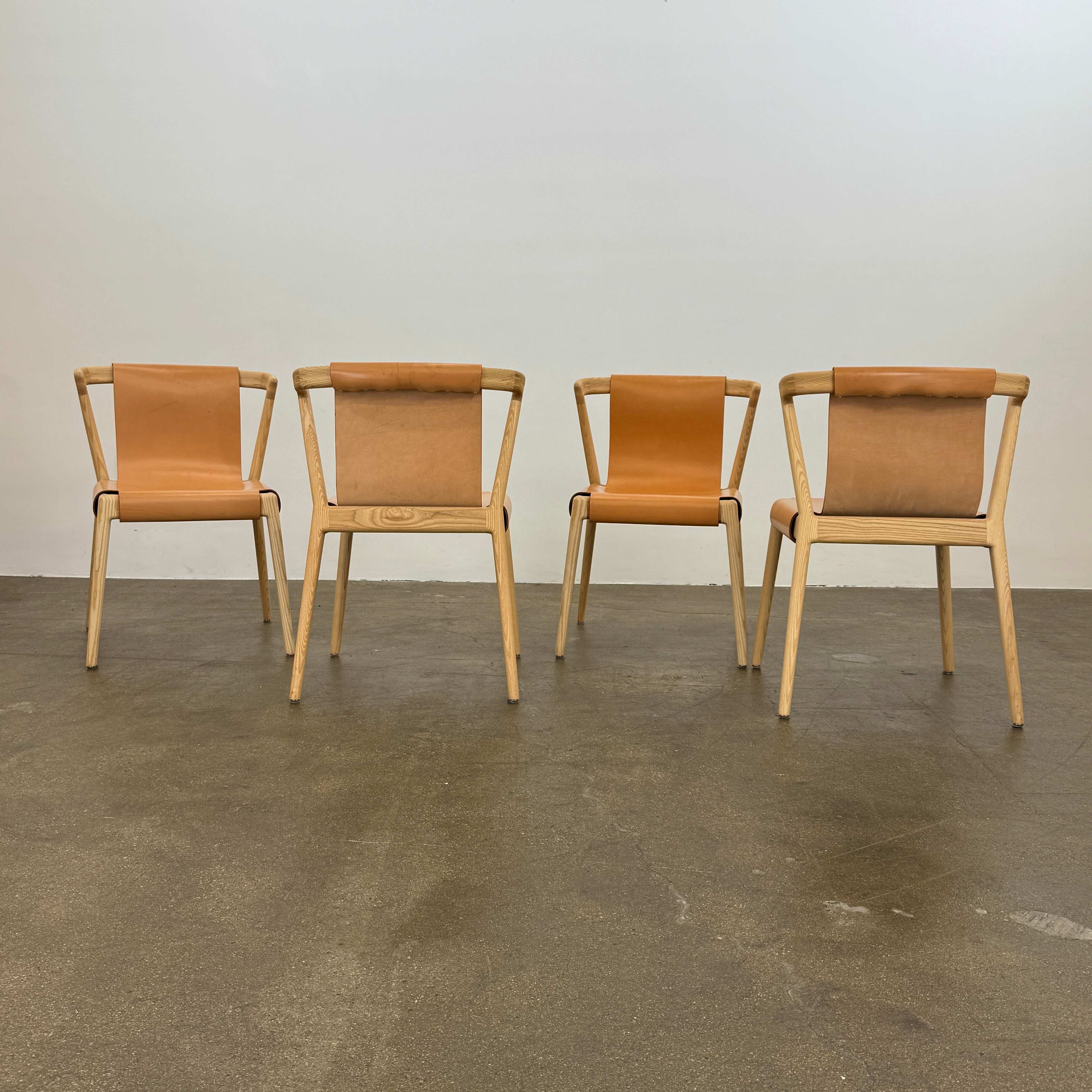 The Tom Feraday Pieman Dining Chair Set of 4 features Hydrowood timber frames and light brown leather seats and backs, offering a perfect blend of elegance and comfort. All four chairs are shown in two rows against a plain white background.