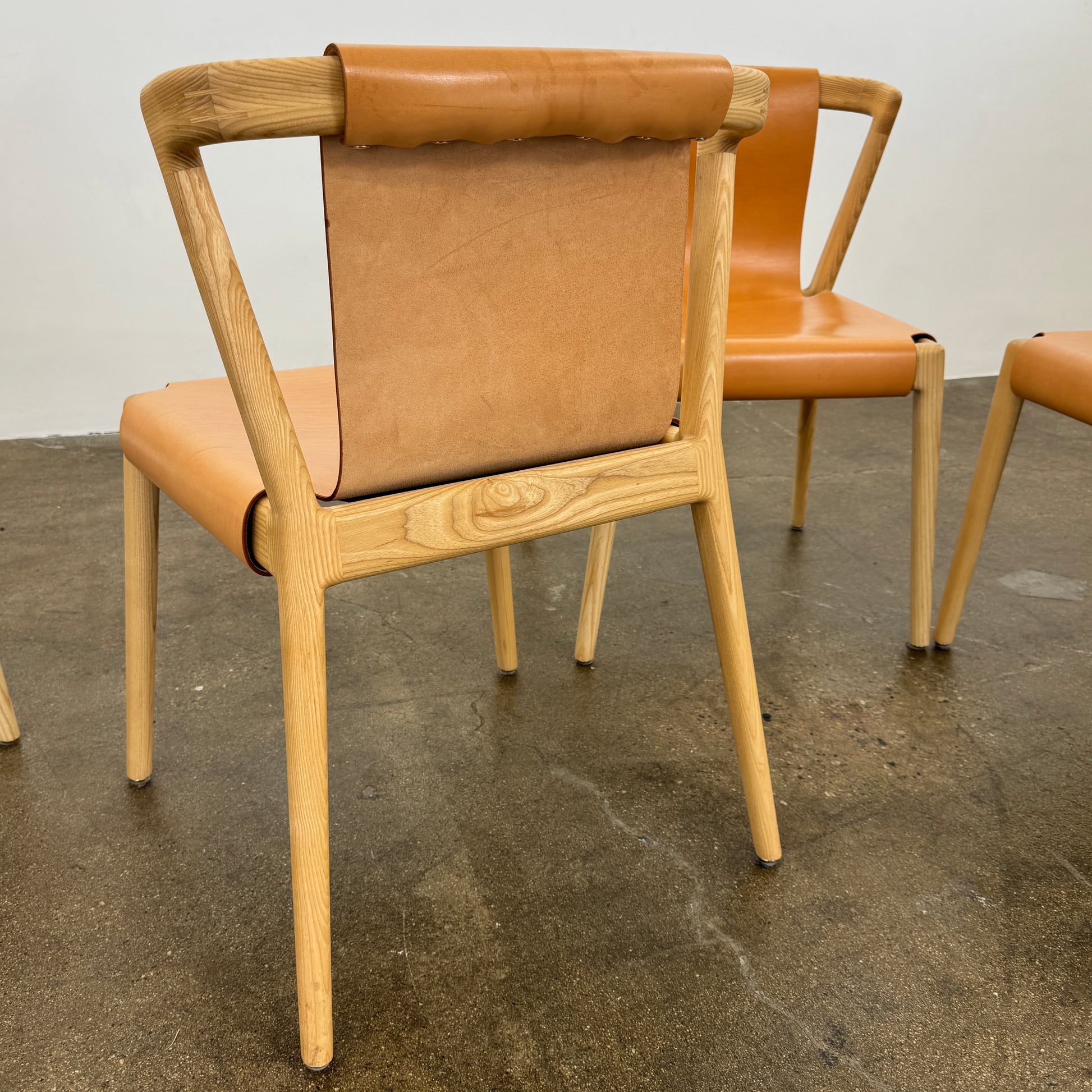 The Tom Feraday Pieman Dining Chair Set of 4 features Hydrowood timber frames and light brown leather seats and backs, offering a perfect blend of elegance and comfort. All four chairs are shown in two rows against a plain white background.