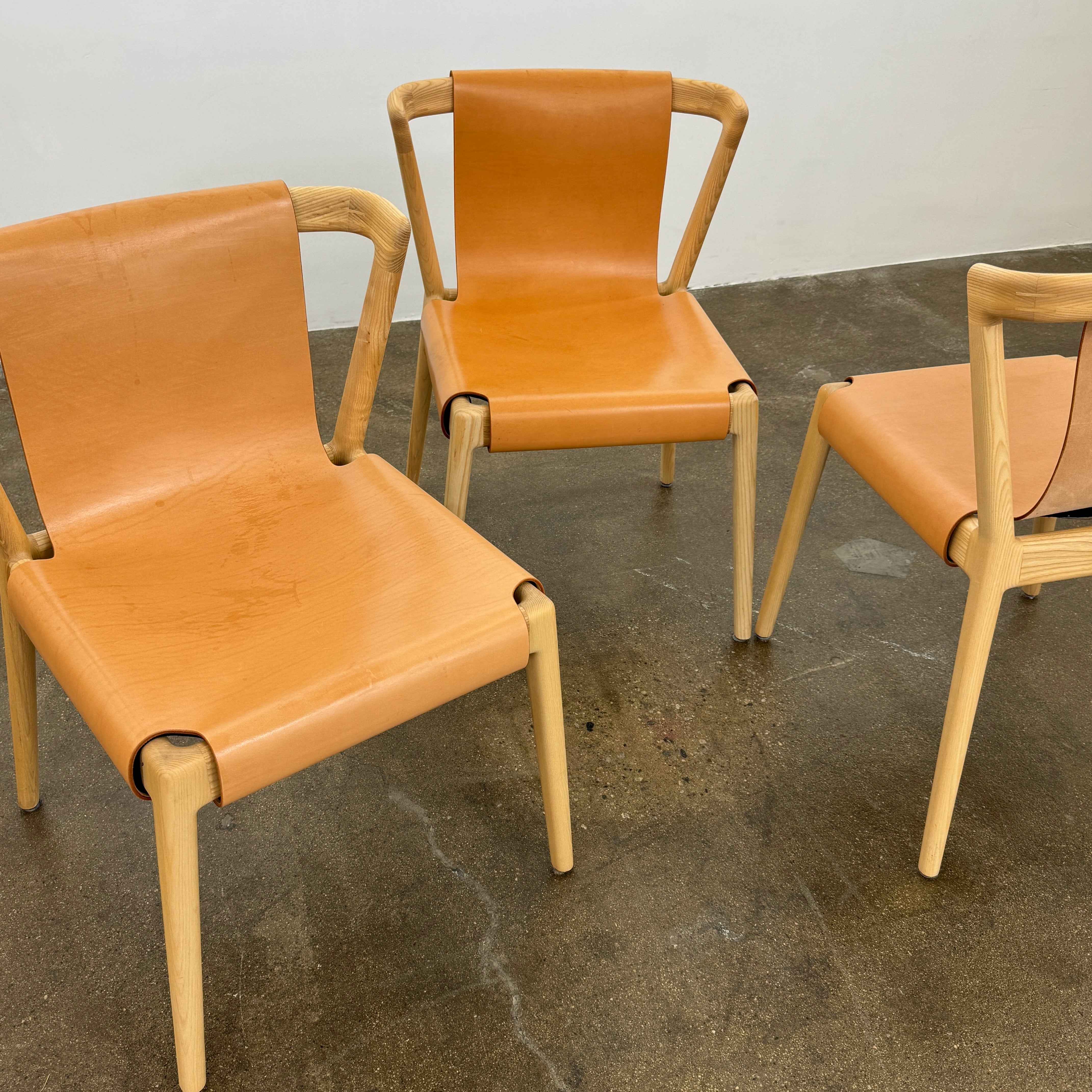 The Tom Feraday Pieman Dining Chair Set of 4 features Hydrowood timber frames and light brown leather seats and backs, offering a perfect blend of elegance and comfort. All four chairs are shown in two rows against a plain white background.