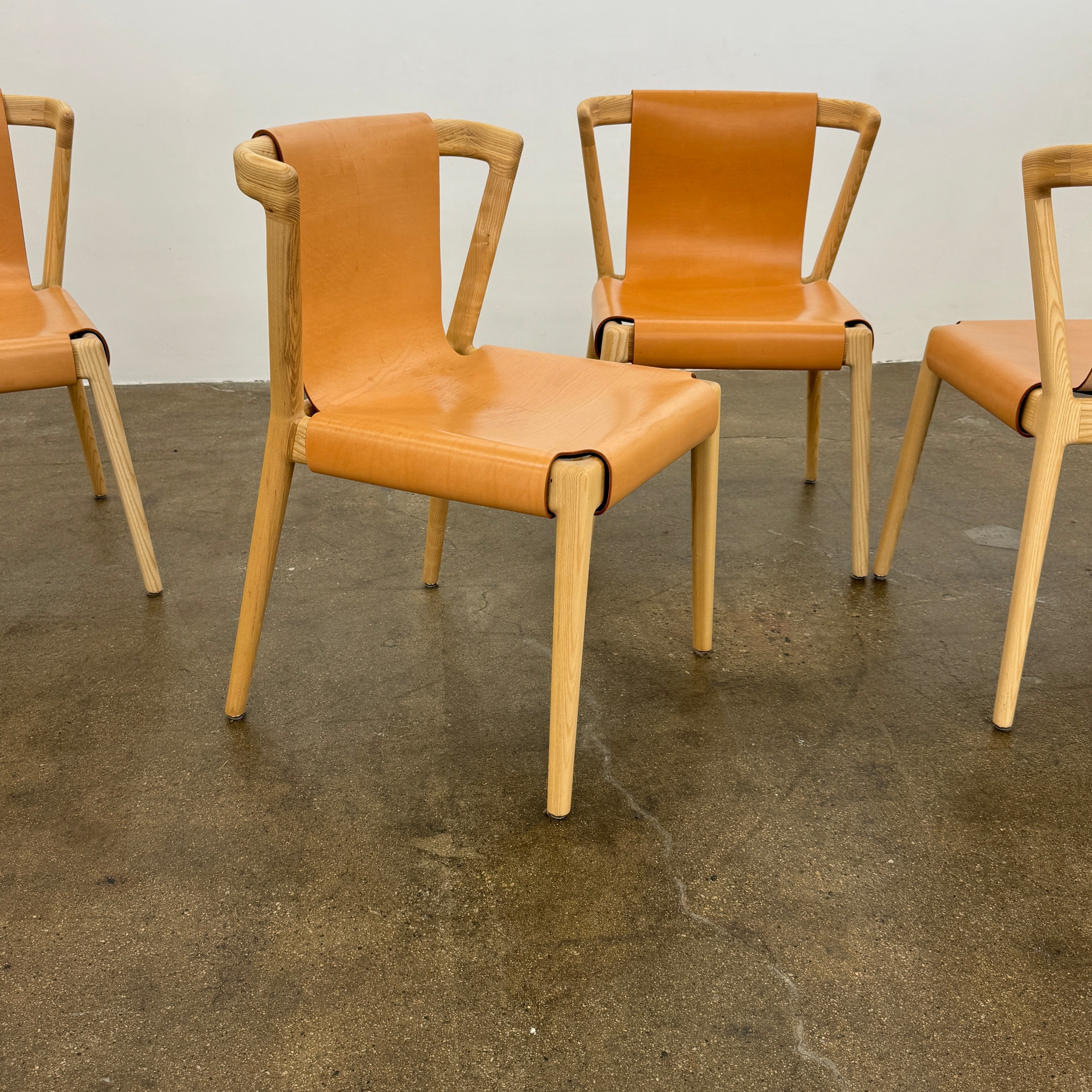 The Tom Feraday Pieman Dining Chair Set of 4 features Hydrowood timber frames and light brown leather seats and backs, offering a perfect blend of elegance and comfort. All four chairs are shown in two rows against a plain white background.