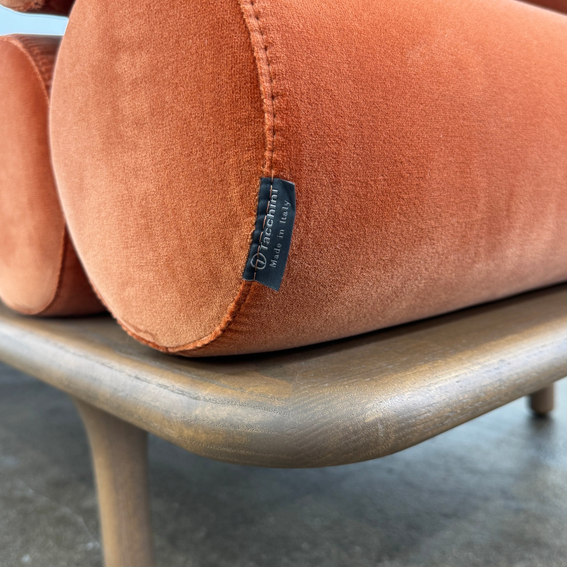 The Tacchini Five to Nine Day Bed by Tacchini features orange cylindrical cushions on a wooden frame—an ideal modern piece for an artist studio, shown here against a plain white background.