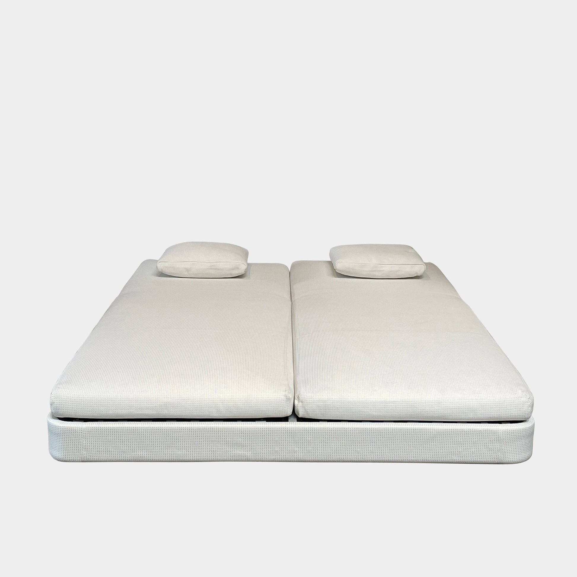 An adjustable white Paola Lenti Cove Double Sunbed by Paola Lenti features two separate reclining mattresses and matching pillows, perfect for outdoor lounging.