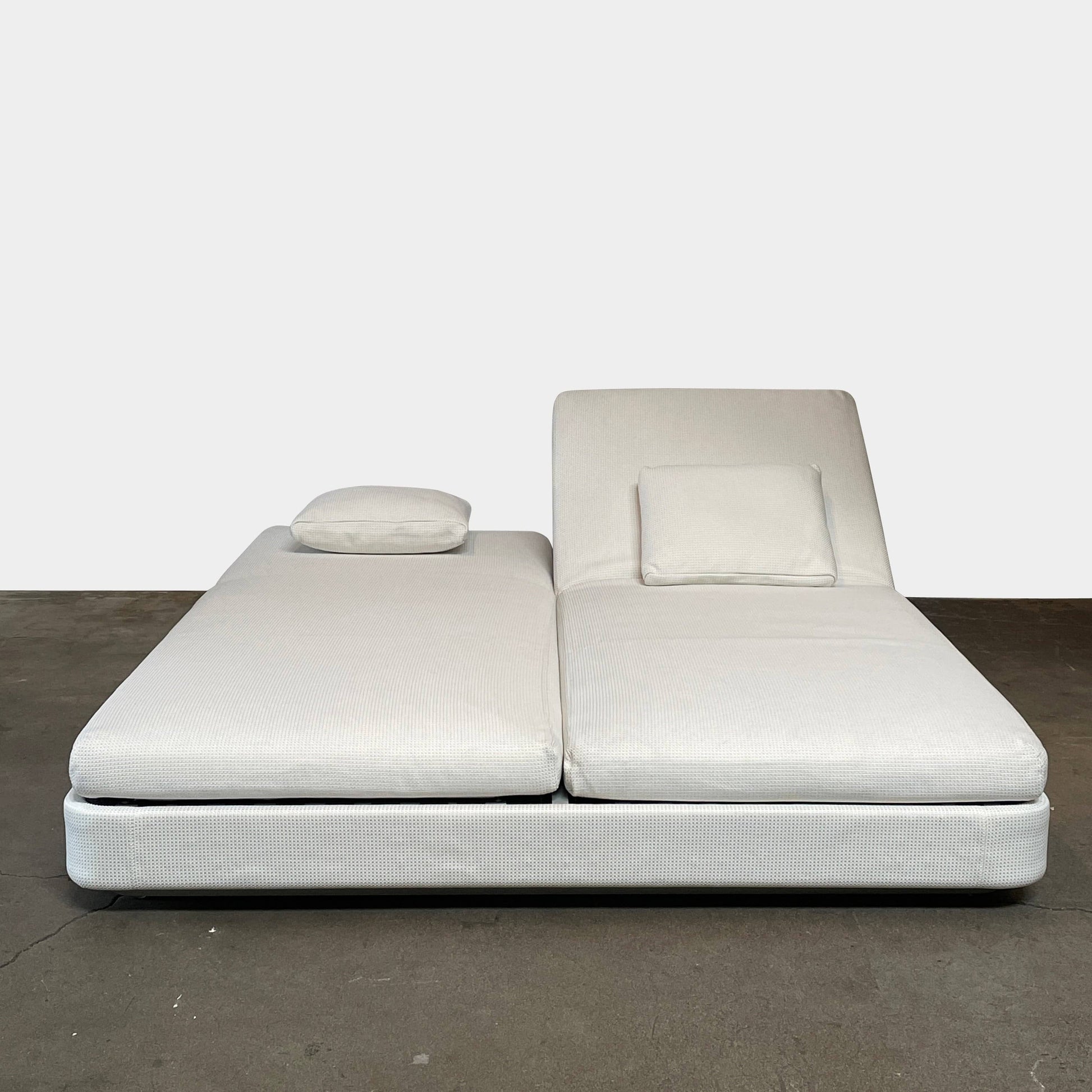 An adjustable white Paola Lenti Cove Double Sunbed by Paola Lenti features two separate reclining mattresses and matching pillows, perfect for outdoor lounging.