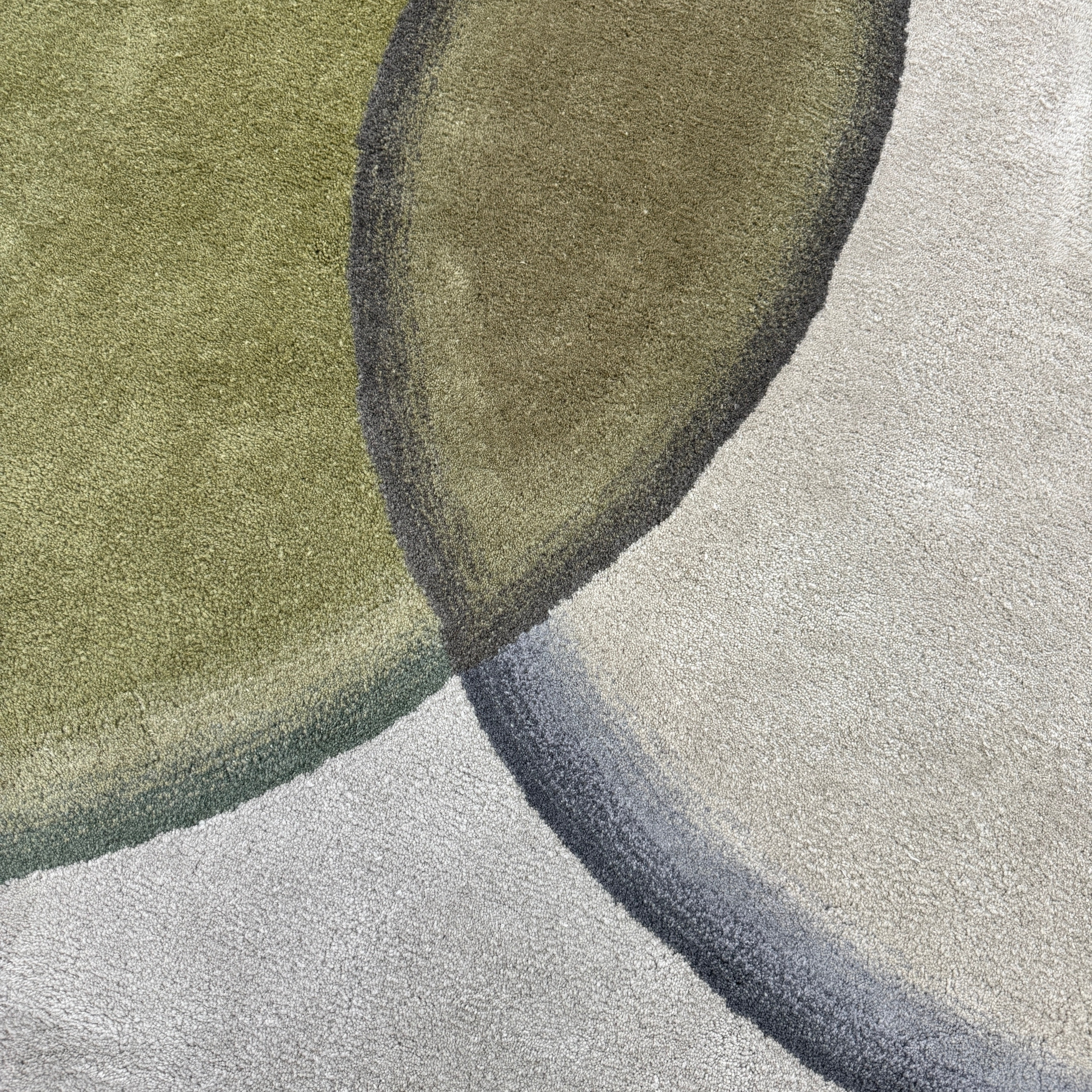 The Gan Crystal Rug by Gan, designed by Charlotte Lancelot, displays three overlapping circles in yellow, green, and beige set against a deep brown background.