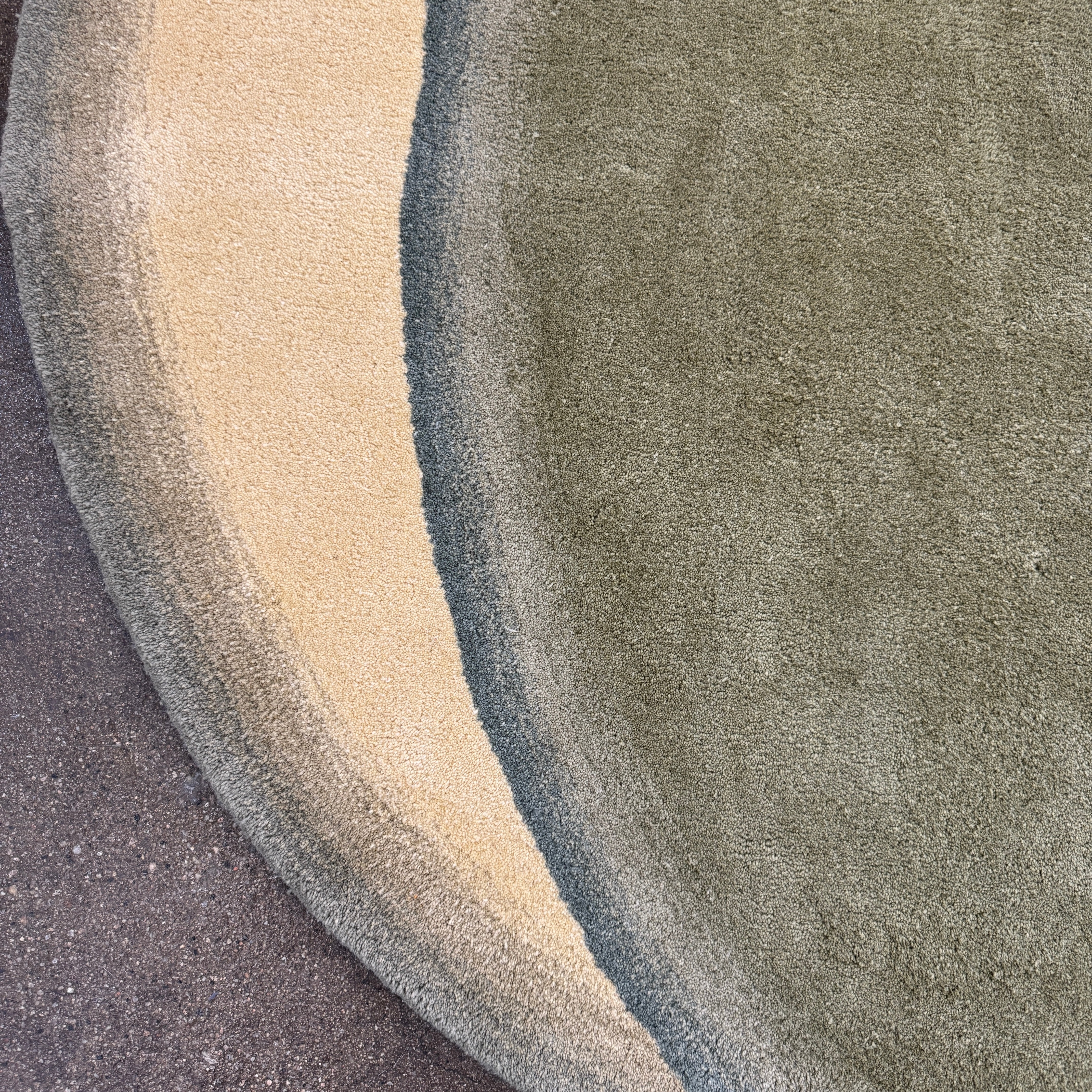 The Gan Crystal Rug by Gan, designed by Charlotte Lancelot, displays three overlapping circles in yellow, green, and beige set against a deep brown background.