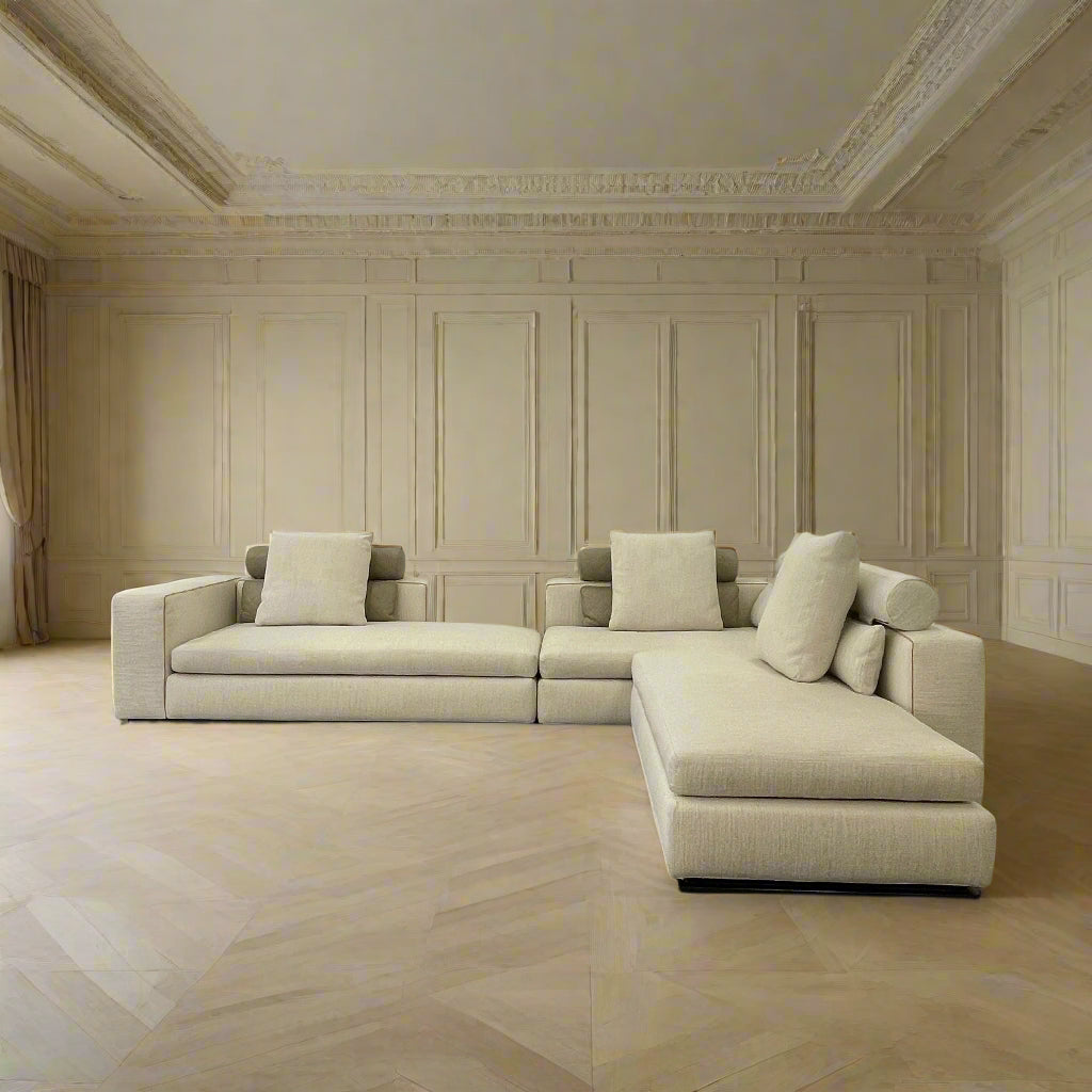 The Minotti Leonard 3 Piece Sectional by Minotti features an L-shaped beige design with three seat sections, multiple back and side cushions, and a right-side chaise lounge—ideal for an elegant living space—shown on a plain white background.