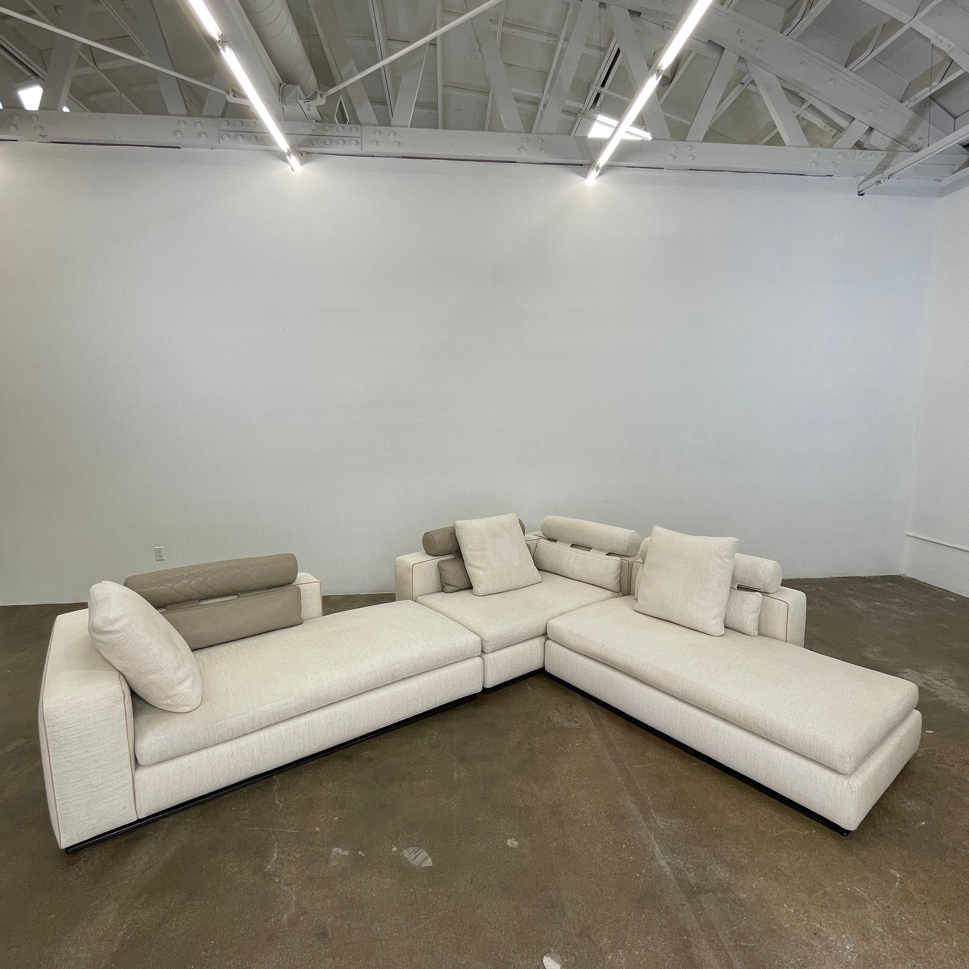 The Minotti Leonard 3 Piece Sectional by Minotti features an L-shaped beige design with three seat sections, multiple back and side cushions, and a right-side chaise lounge—ideal for an elegant living space—shown on a plain white background.